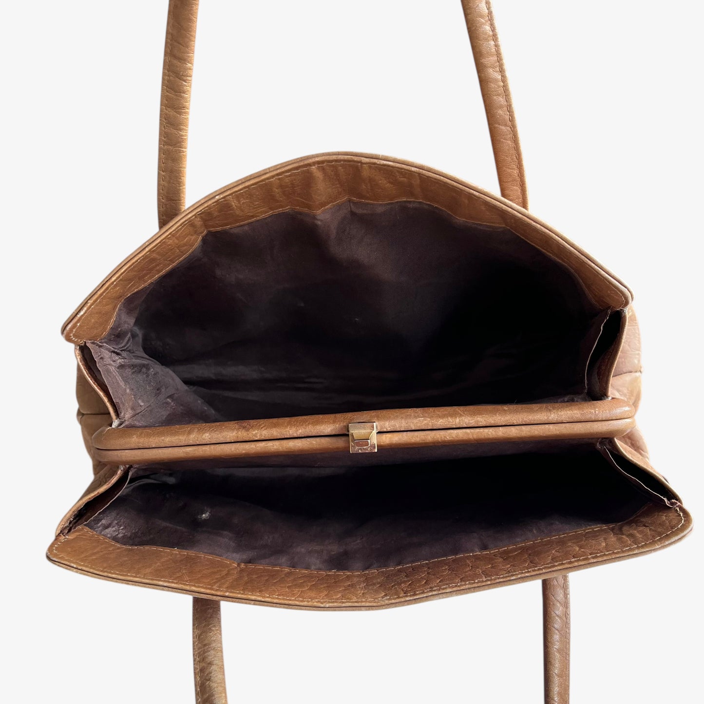 Inside of vintage 1950s crocodile embossed light brown leather shoulder bag on a white background.