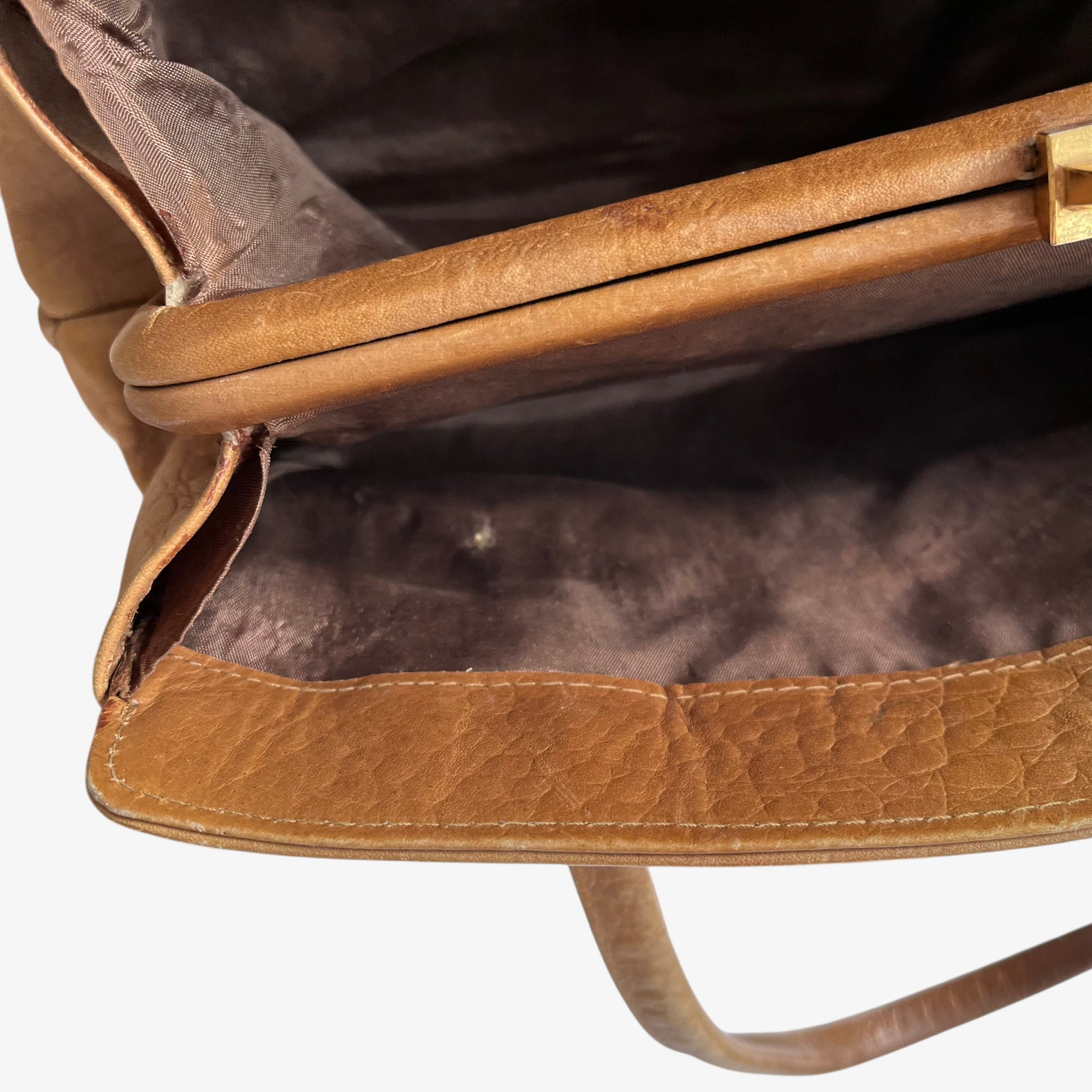 Wear on the inside pocket of a vintage 1950s crocodile embossed light brown leather shoulder bag.