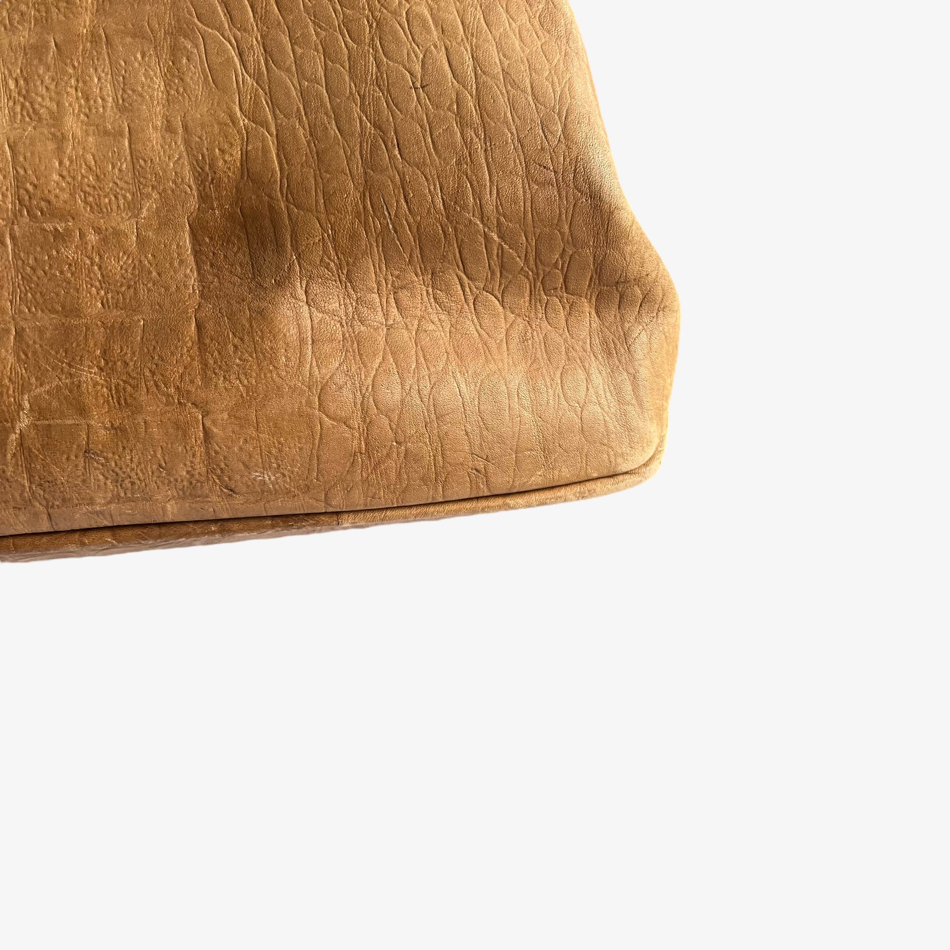 Close up of patina on a vintage 1950s crocodile embossed light brown leather shoulder bag.