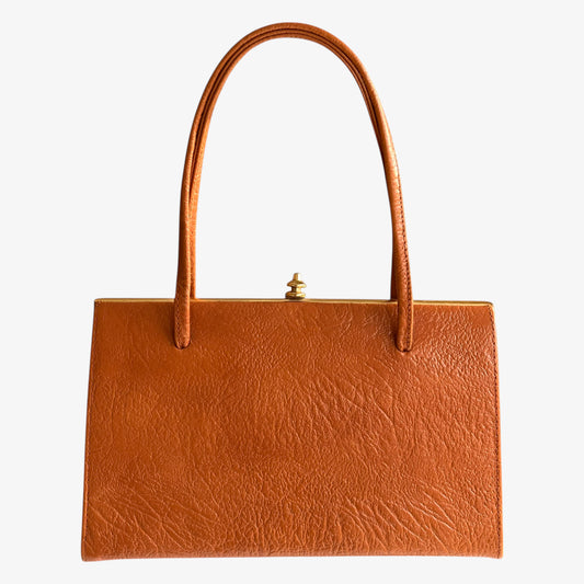 Vintage 1950s Freedex small orange leather frame bag on a white background.