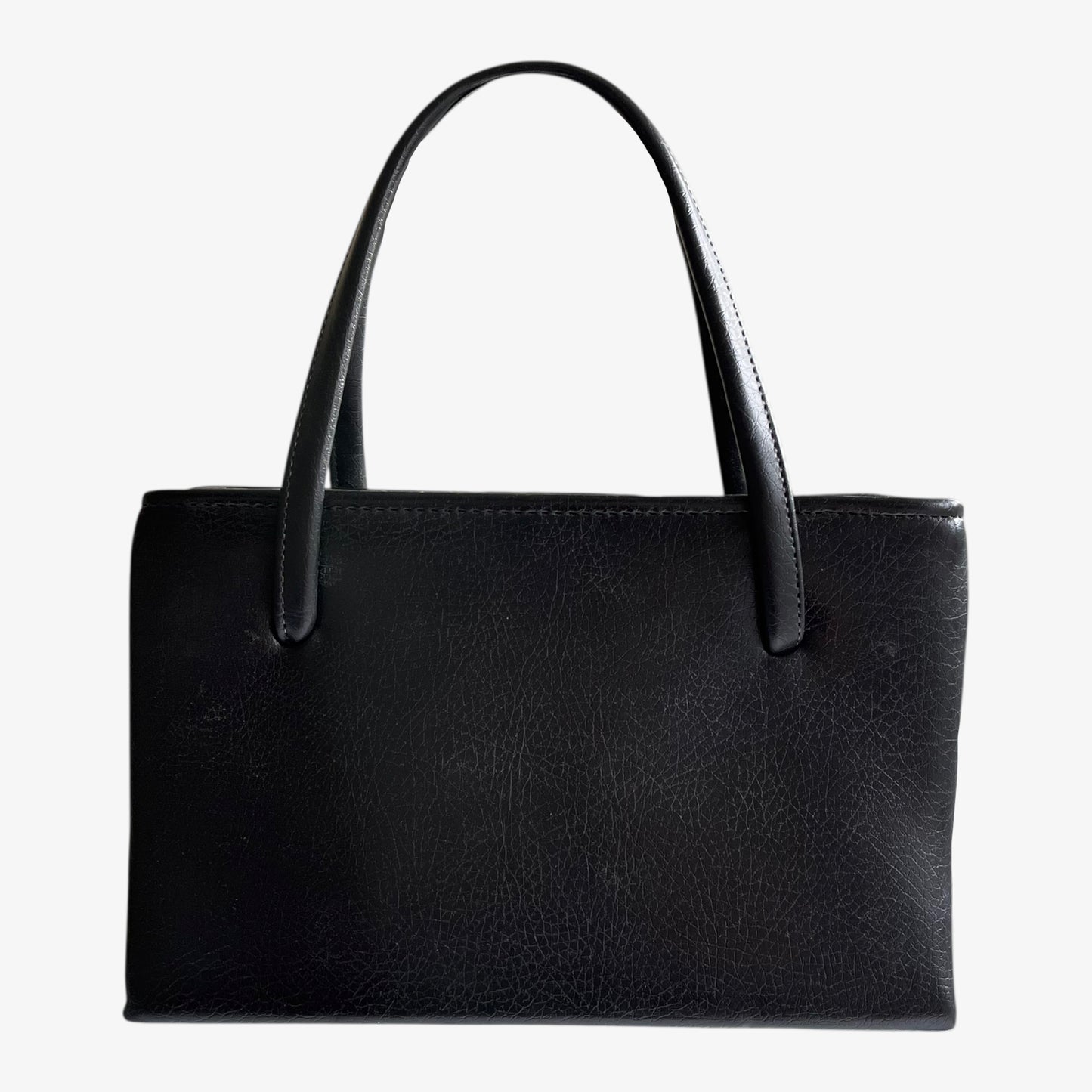 Back of a vintage 1960s black pebbled leather shoulder bag on a white background.