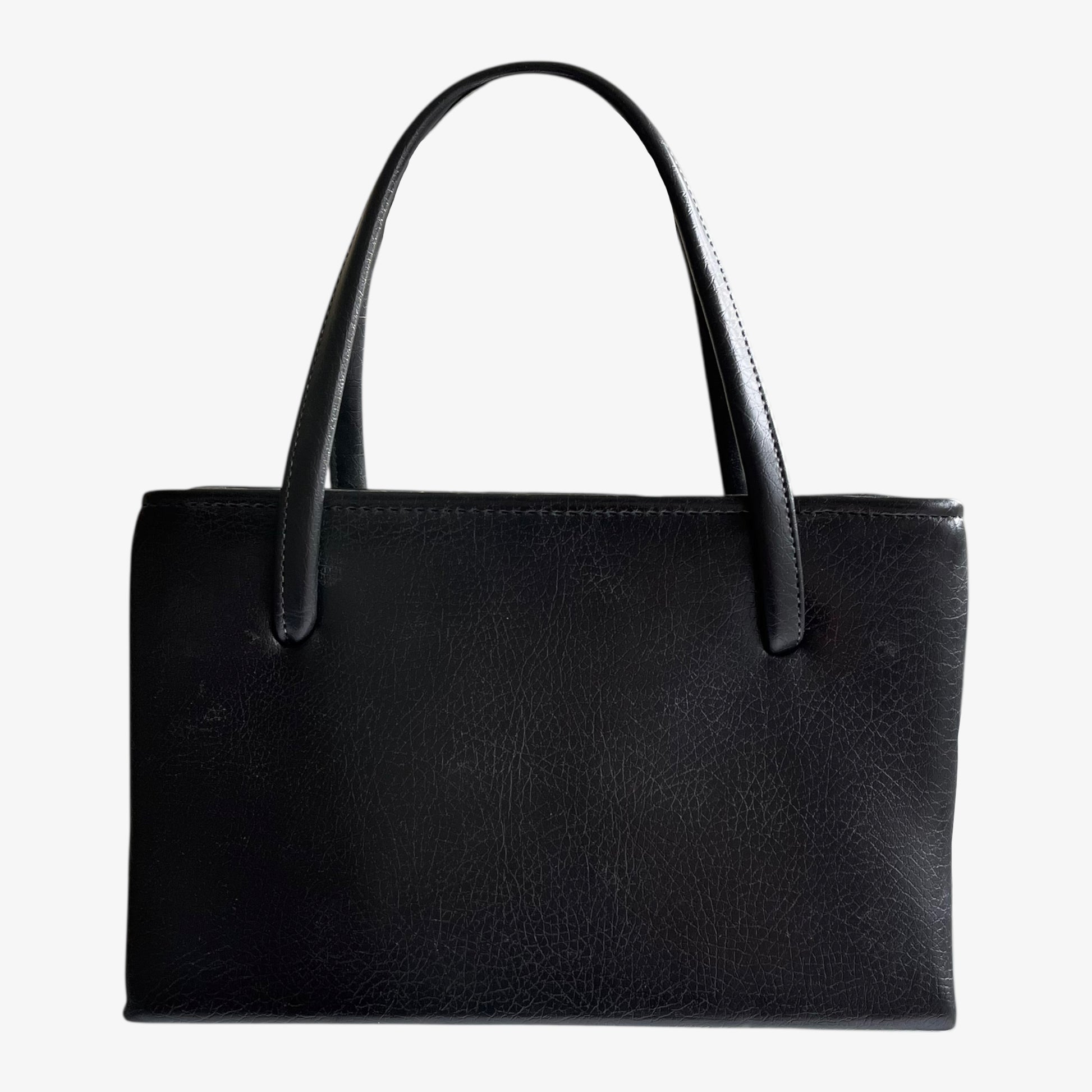 Back of a vintage 1960s black pebbled leather shoulder bag on a white background.
