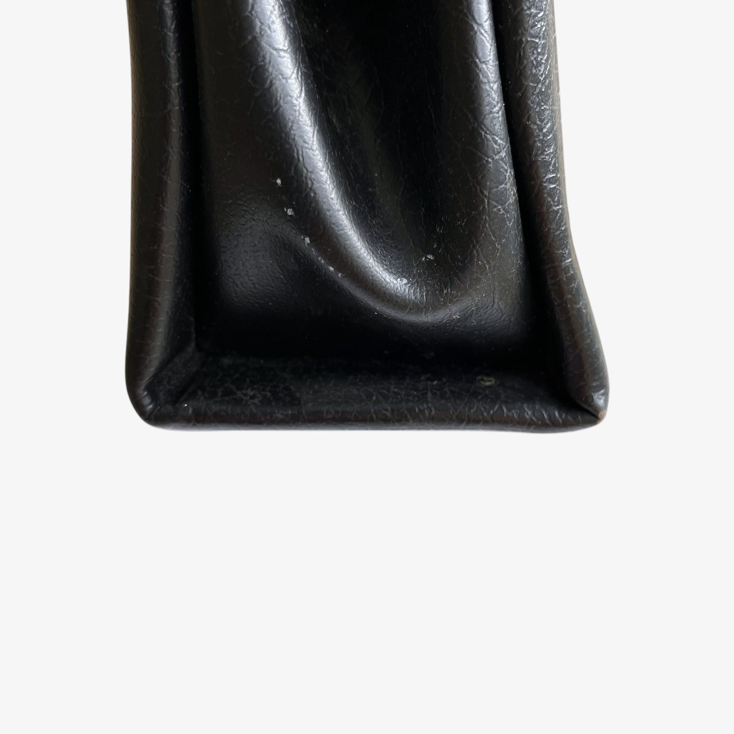 Patina on the bottom of a vintage 1960s black pebbled leather shoulder bag.
