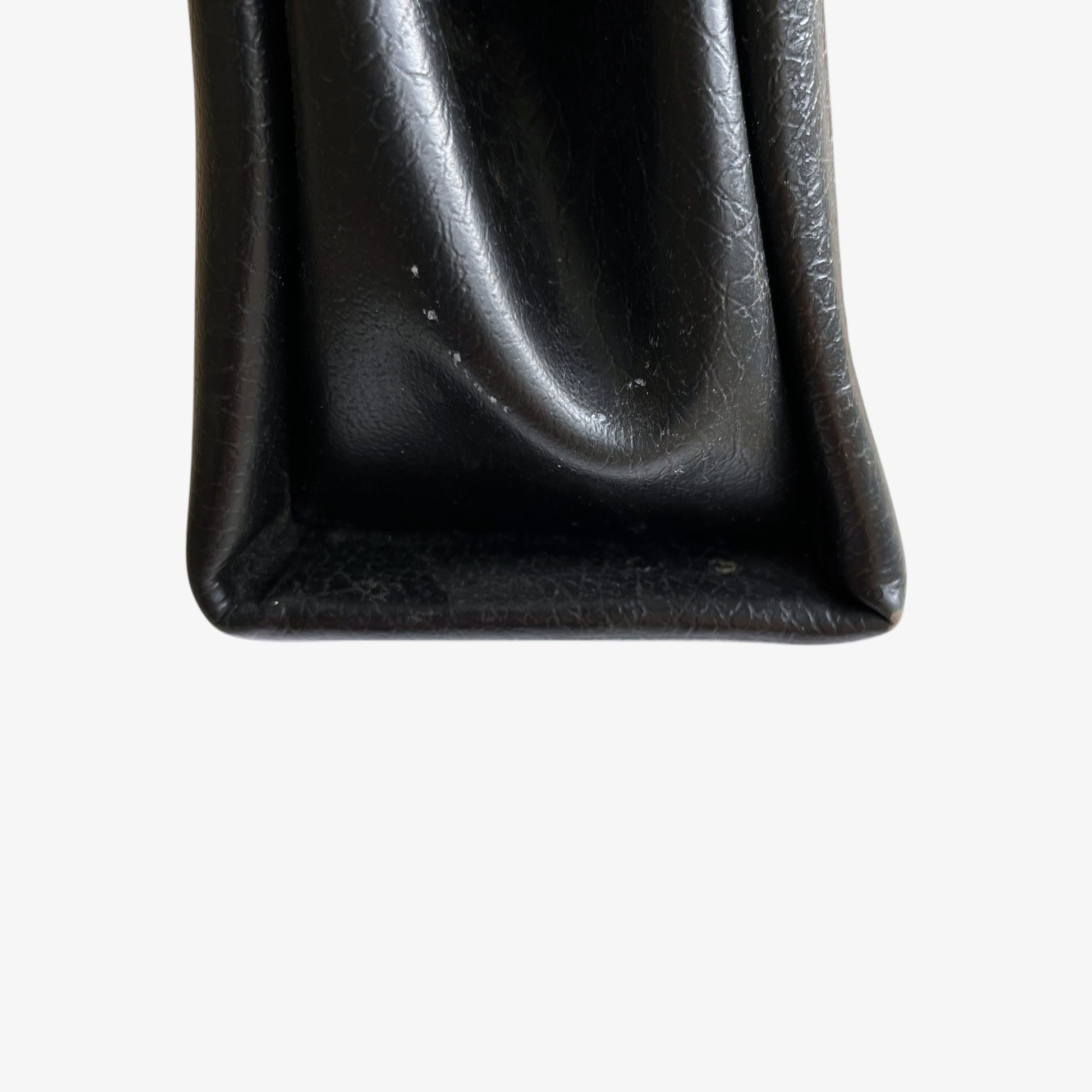Patina on the bottom of a vintage 1960s black pebbled leather shoulder bag.