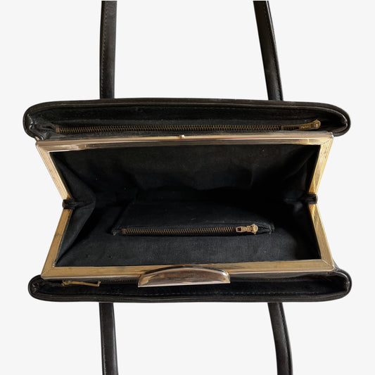 Close up of multiple zipped pockets inside of a vintage 1960s black pebbled leather shoulder bag.