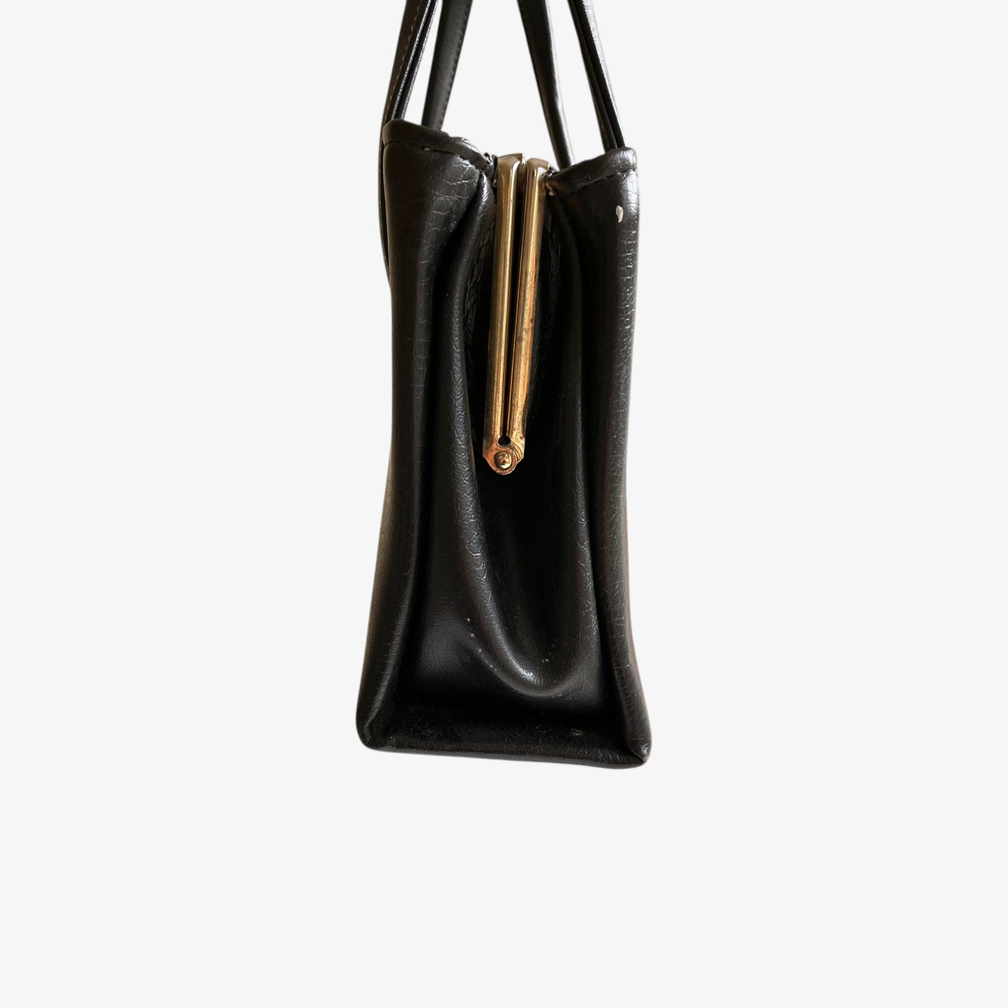 Side view of a vintage 1960s black pebbled leather shoulder bag on a white background.