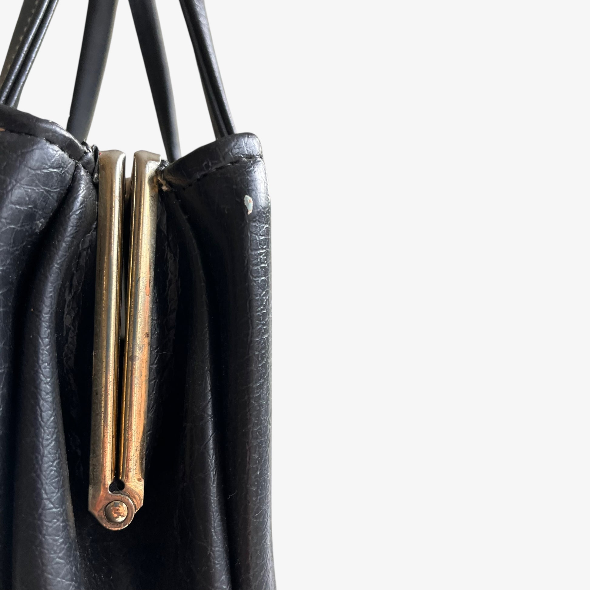 Close up of patina on a vintage 1960s black pebbled leather shoulder bag.