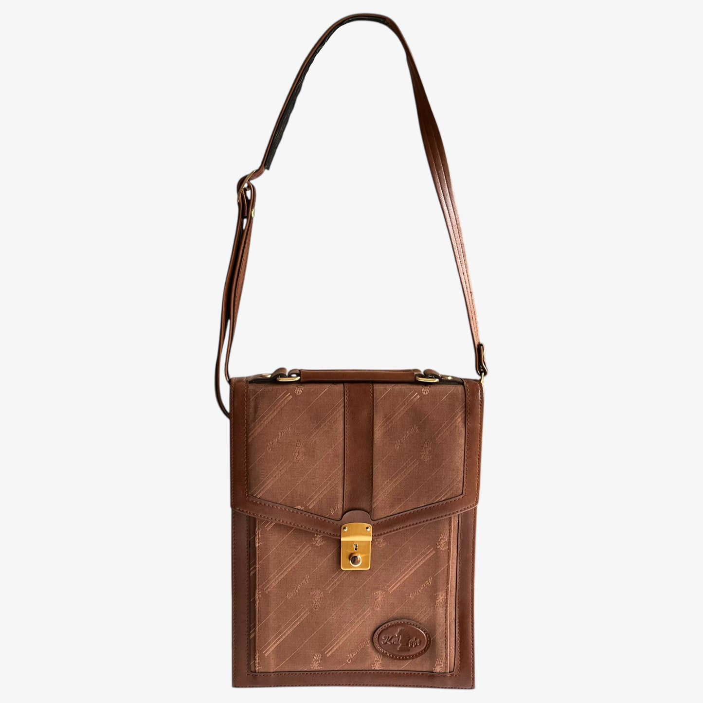 Vintage 1970s brown canvas and leather crossbody messenger bag with a monogram print and a gold clasp on a white background.