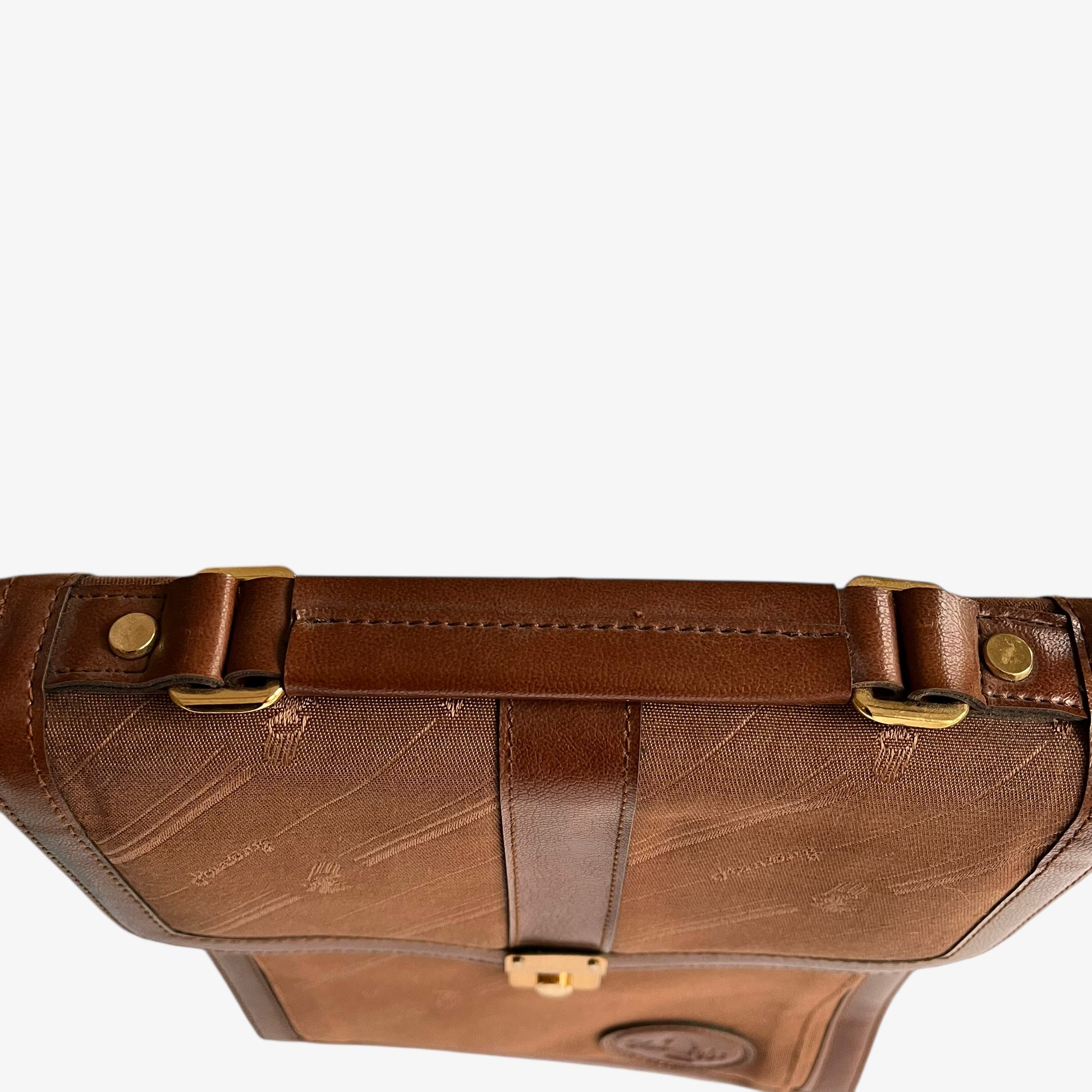Close up of brown leather handle on a vintage 1970s canvas crossbody messenger bag.