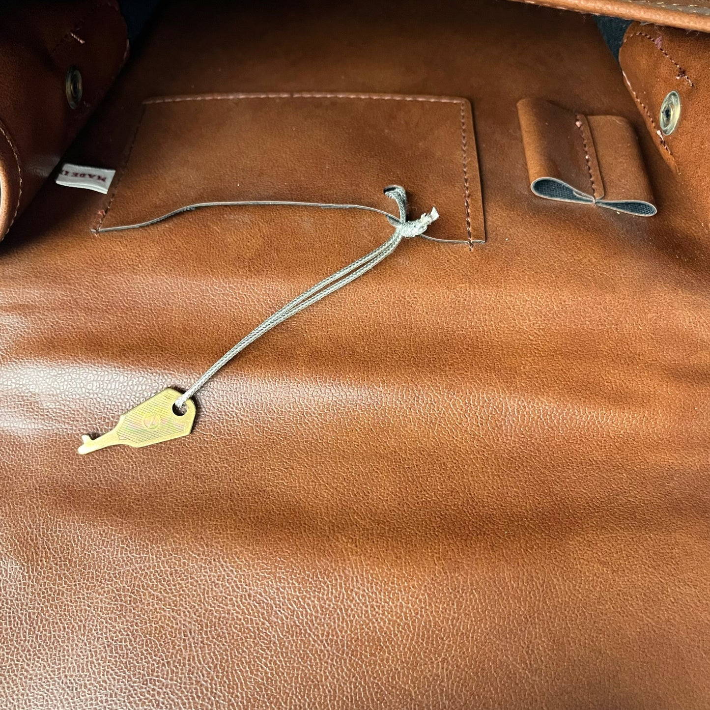 Close up of a key inside of a vintage 1970s brown canvas and leather crossbody messenger bag.