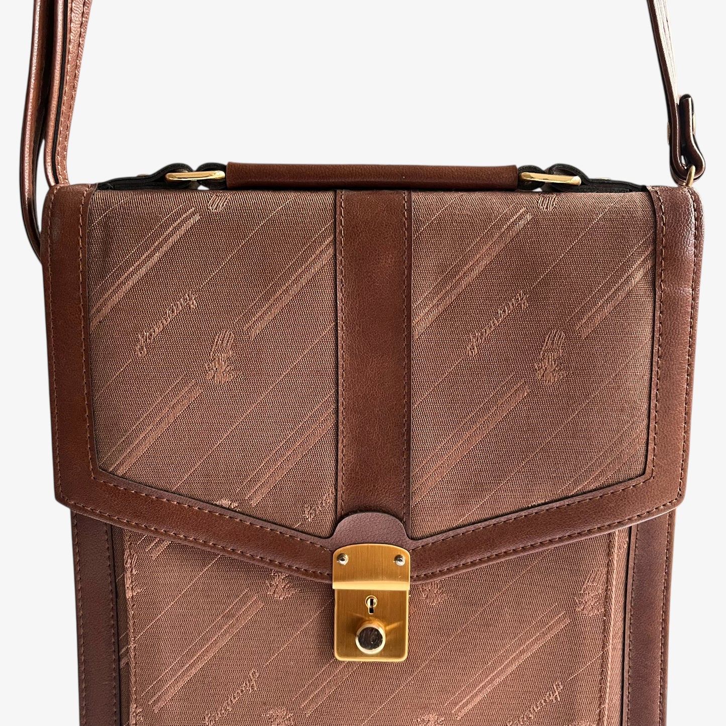 Close up of gold lock clasp on a vintage 1970s brown canvas and leather crossbody messenger bag.