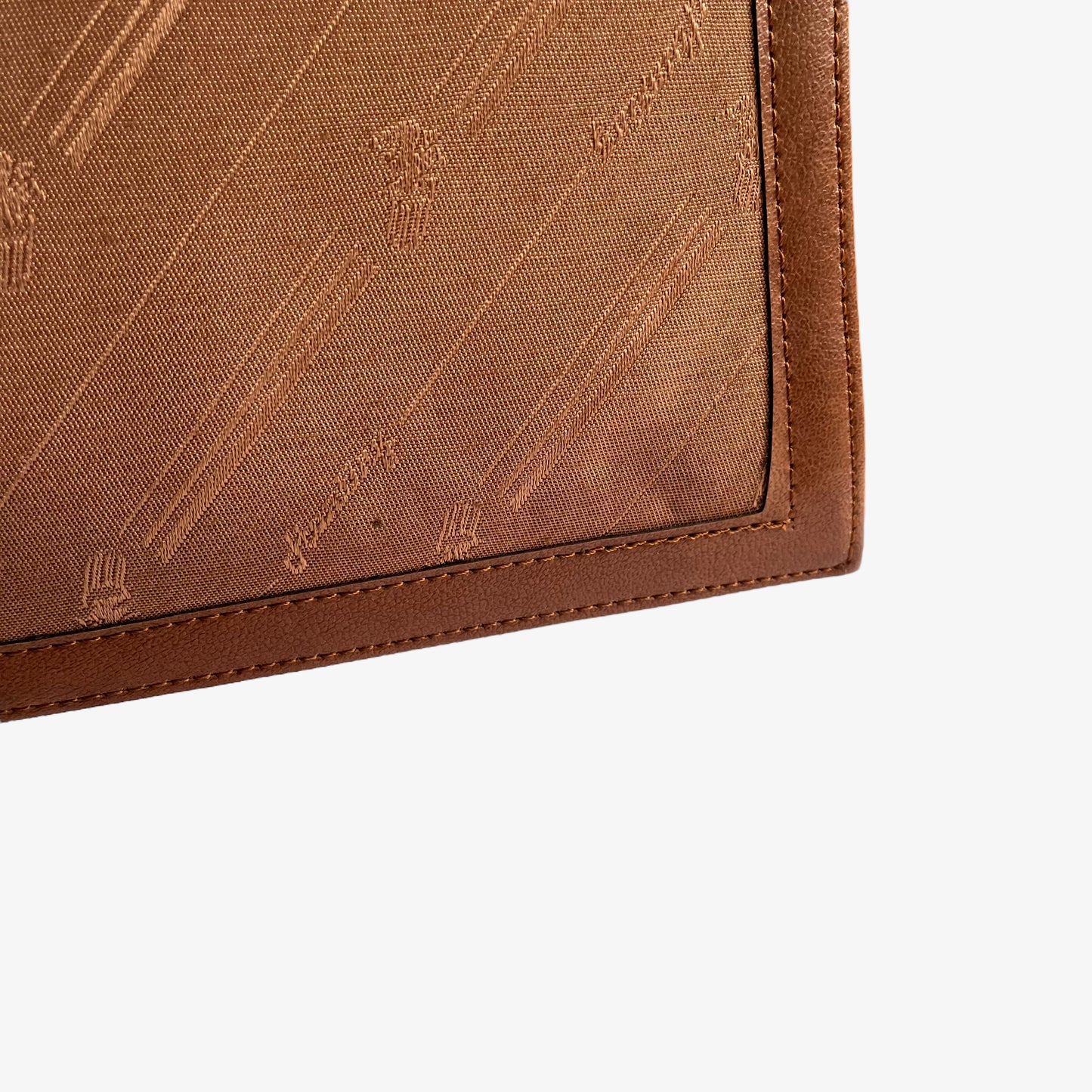 Patina on a vintage 1970s brown canvas and leather crossbody messenger bag with a monogram print.