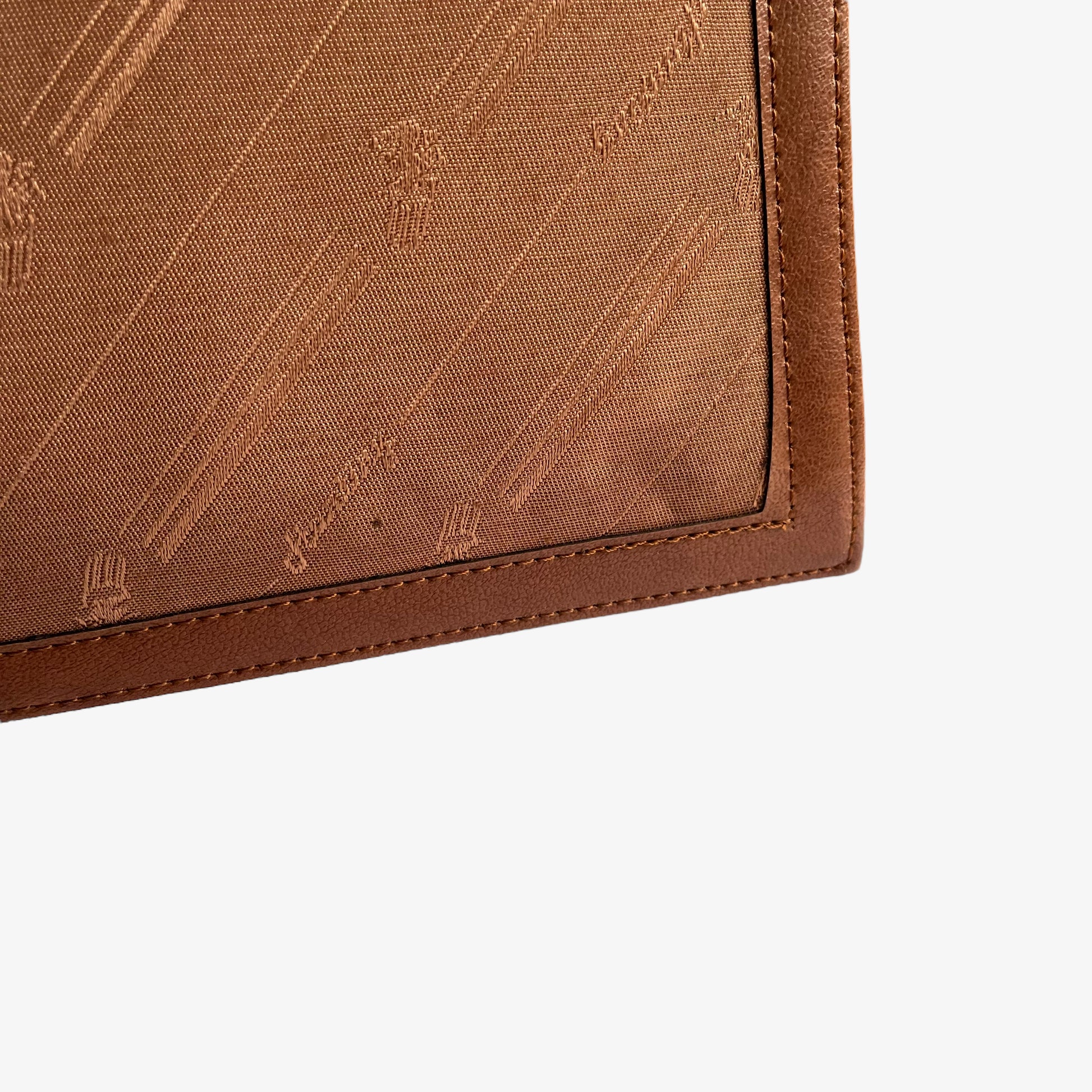Patina on a vintage 1970s brown canvas and leather crossbody messenger bag with a monogram print.