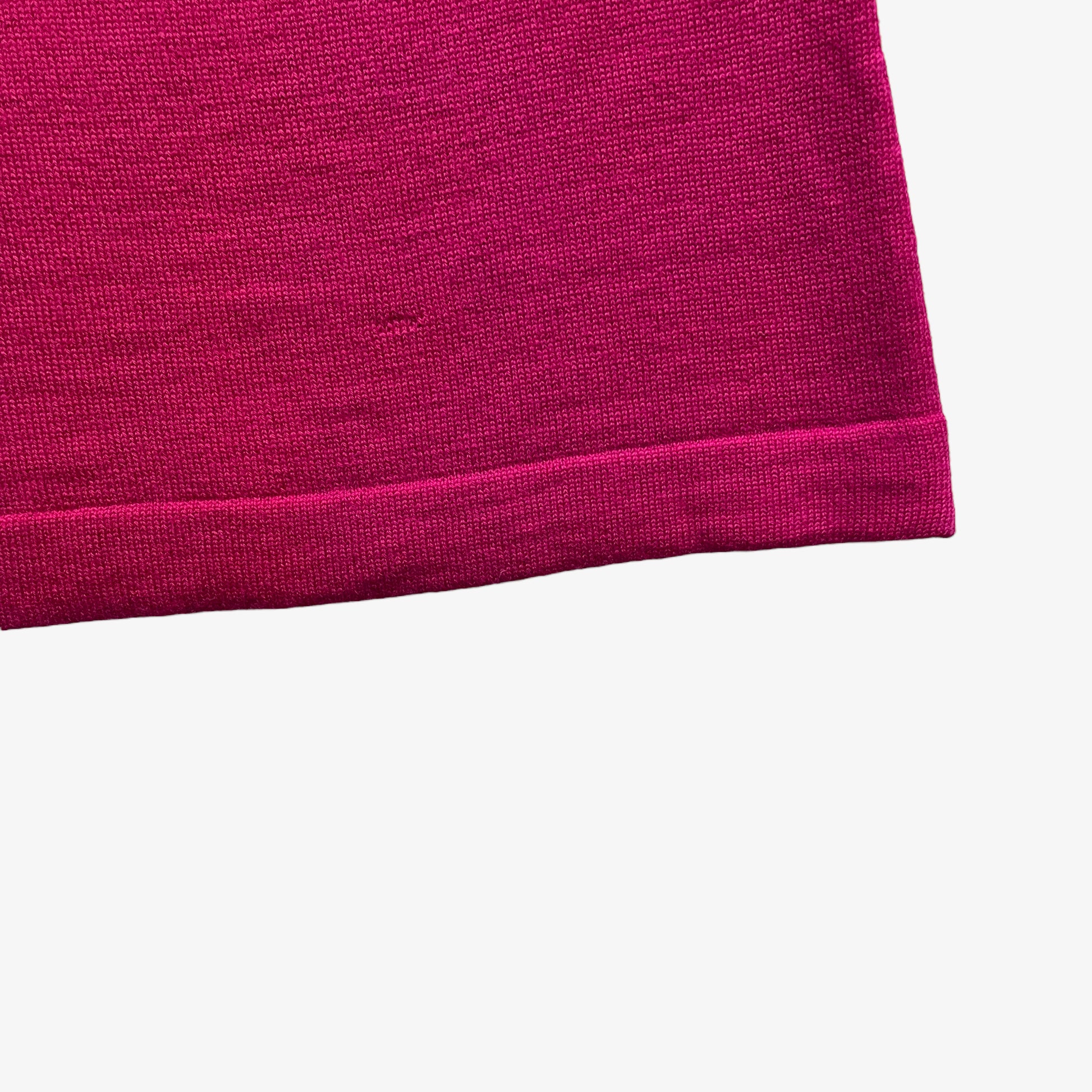 Close up a vintage 1960s pink turtleneck jumper hem on a white background.