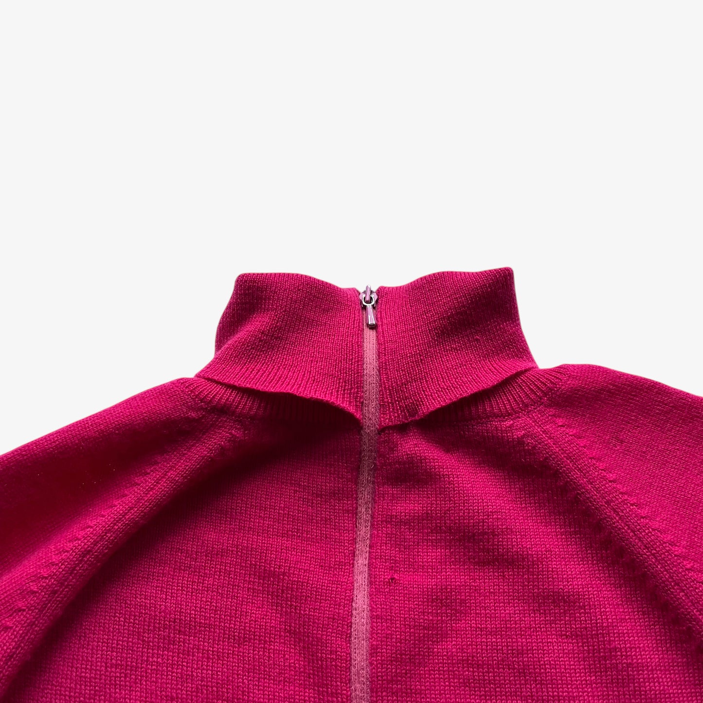 Close up of a vintage 60s pink zip up turtleneck jumper on a white background.