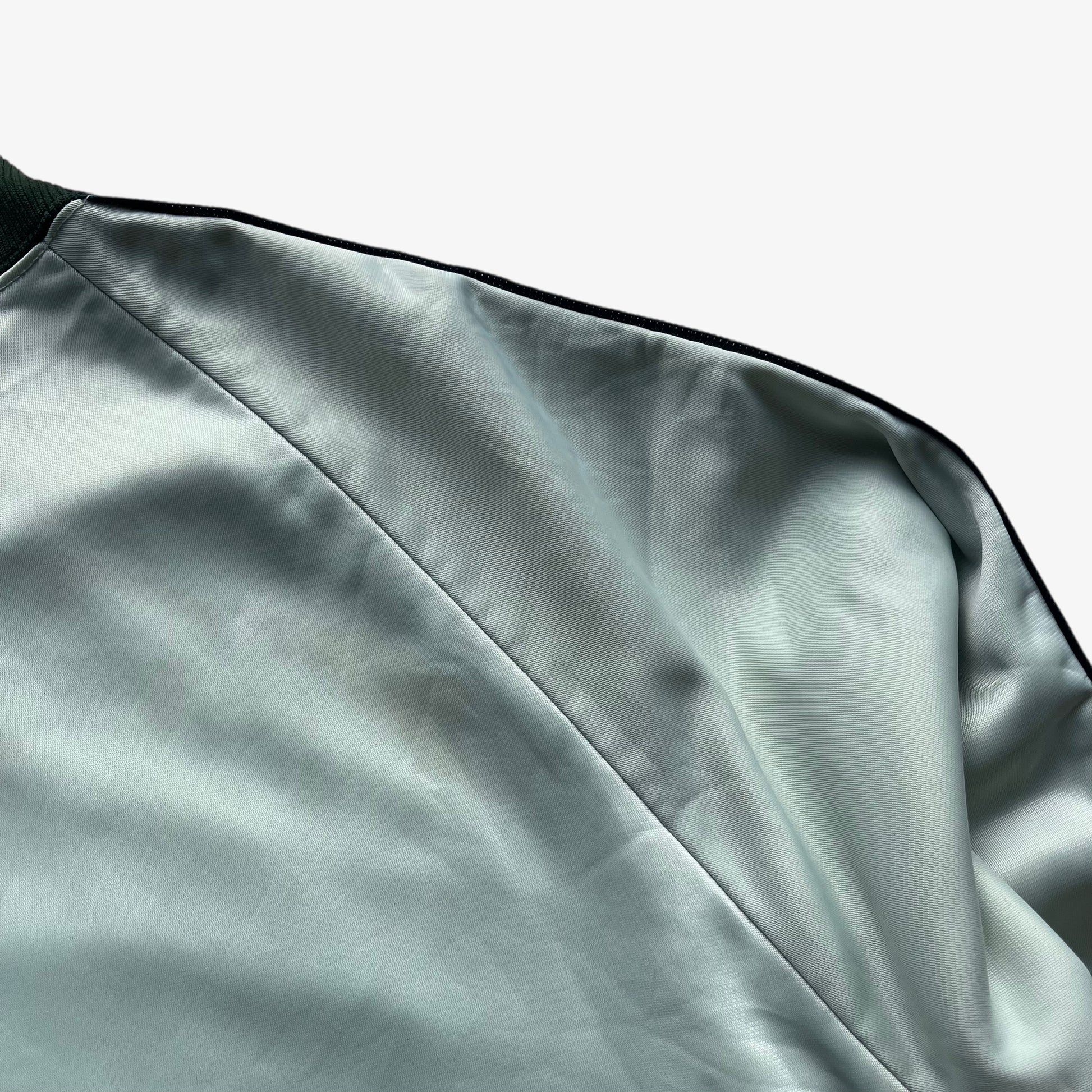Wear on men's vintage 70s Adidas ATP Keyrolan green track jacket.
