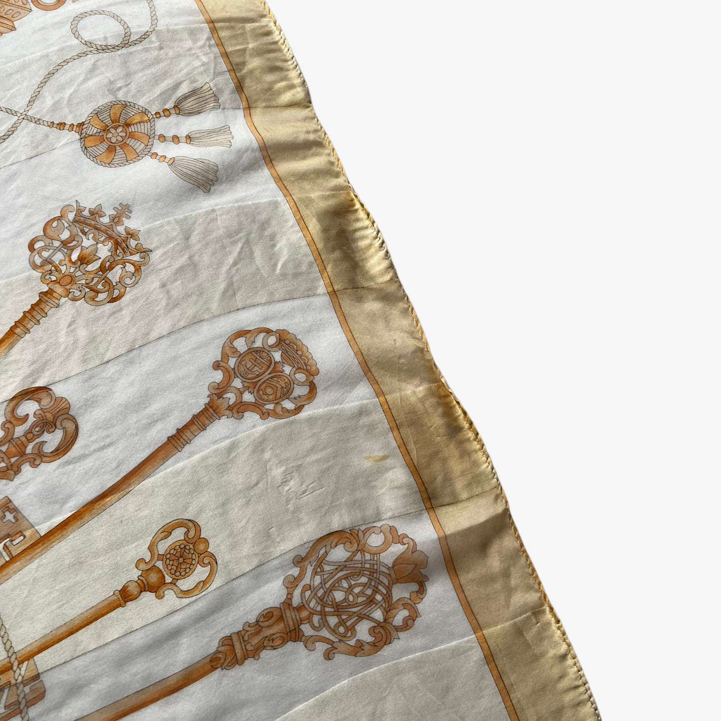 Hem on a women's vintage 80s Balenciaga Paris yellow silk scarf with a gold baroque style key print.