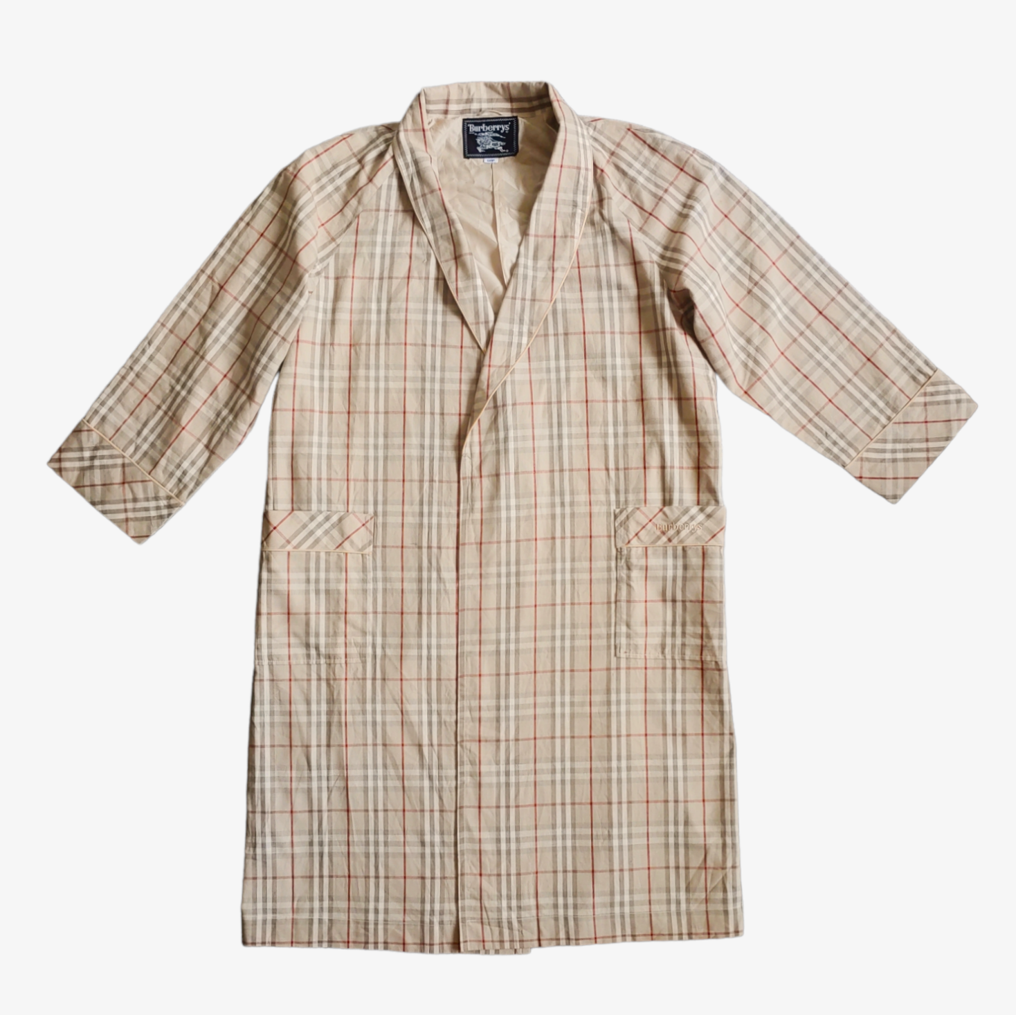 A vintage 1980s men's Burberry nova check robe in beige, brown, and grey checkered pattern, with two side pockets and a V-neckline.