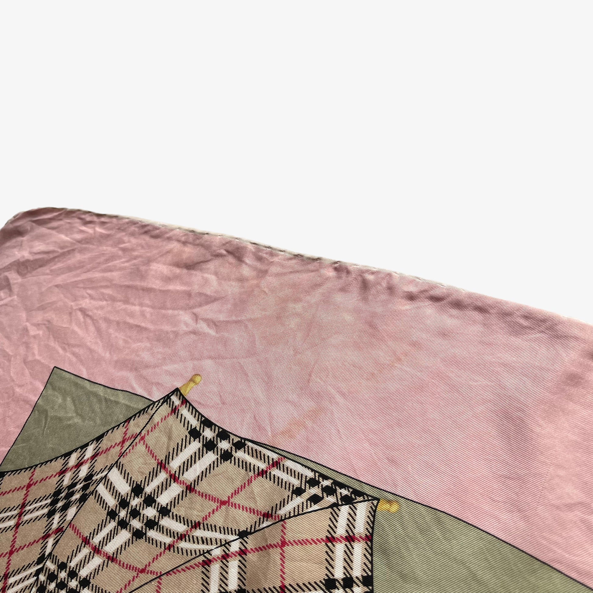 Hand rolled edges of women's vintage 80s Burberry nova check umbrella print pink silk scarf.
