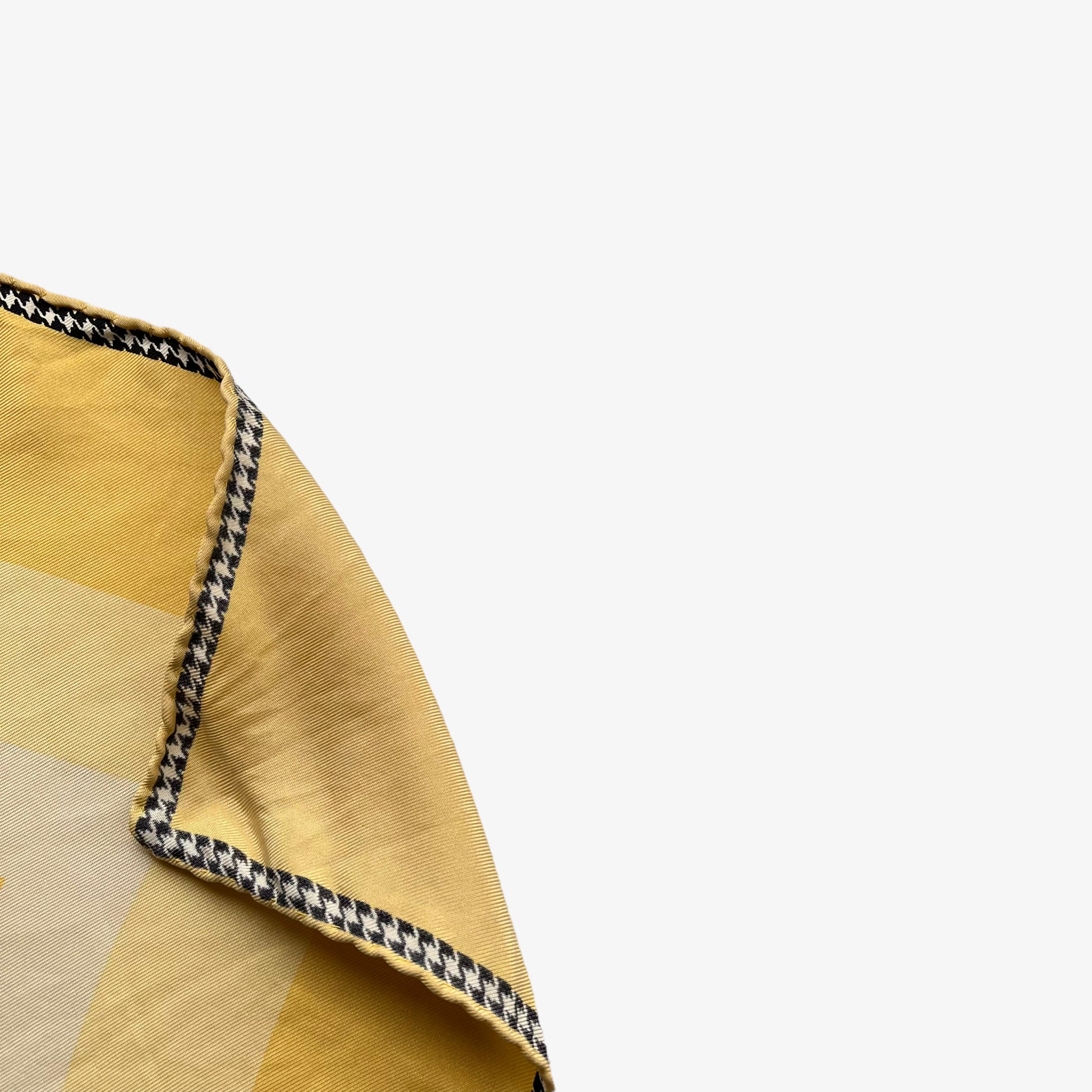 Hand rolled edges of women's vintage 80s Christian Dior art deco wedding dress print yellow silk scarf with a black and white houndstooth trim.
