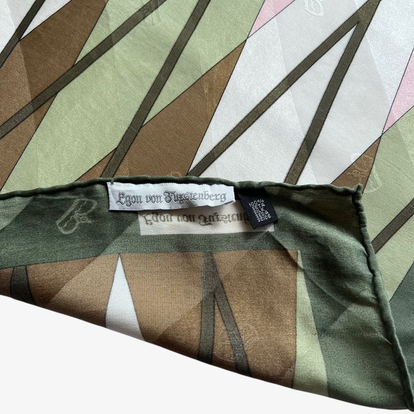 Label and hand rolled edges of women's vintage 80s Egon Von Furstenberg abstract tartan print green silk scarf.