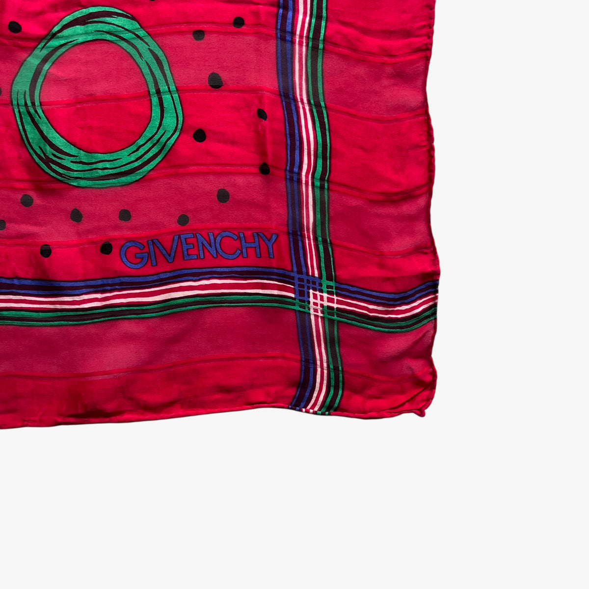 Close up of Givenchy logo on a red silk scarf with a colourful polka dot print.