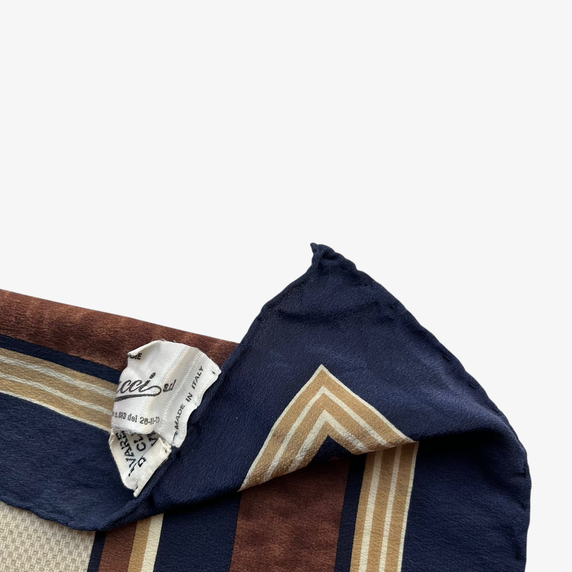 Label of women's vintage 80s Gucci equestrian saddle print brown silk scarf features a GG interlocking pattern.