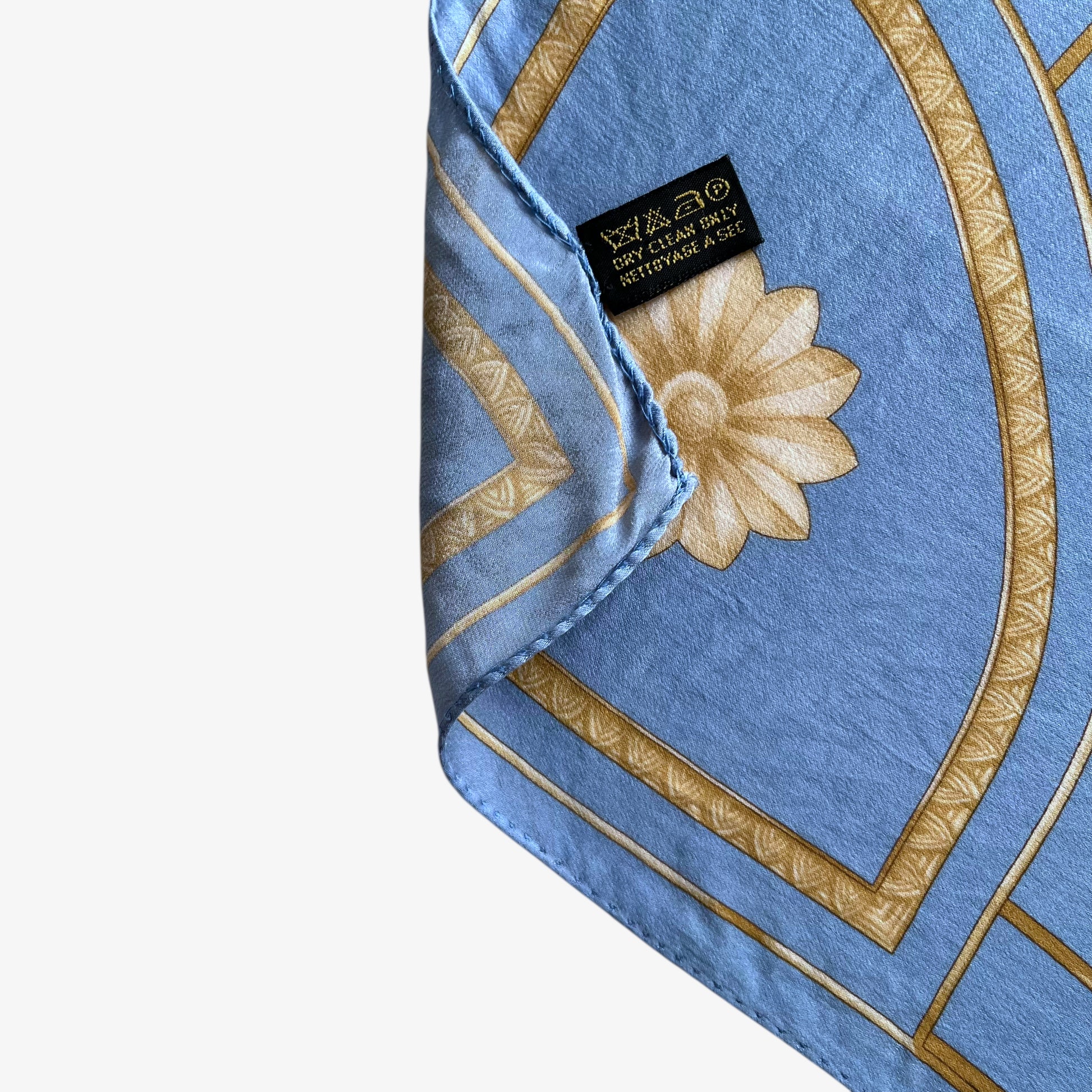 Hand rolled edge on women's vintage 80s Lanvin Paris gold art deco cat print blue silk scarf.