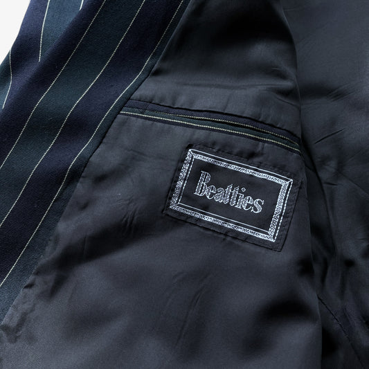 Close-up of a navy and green pinstriped boating blazer lining with a sewn-on label reading 'Beatties' in white script inside a silver glitter border.