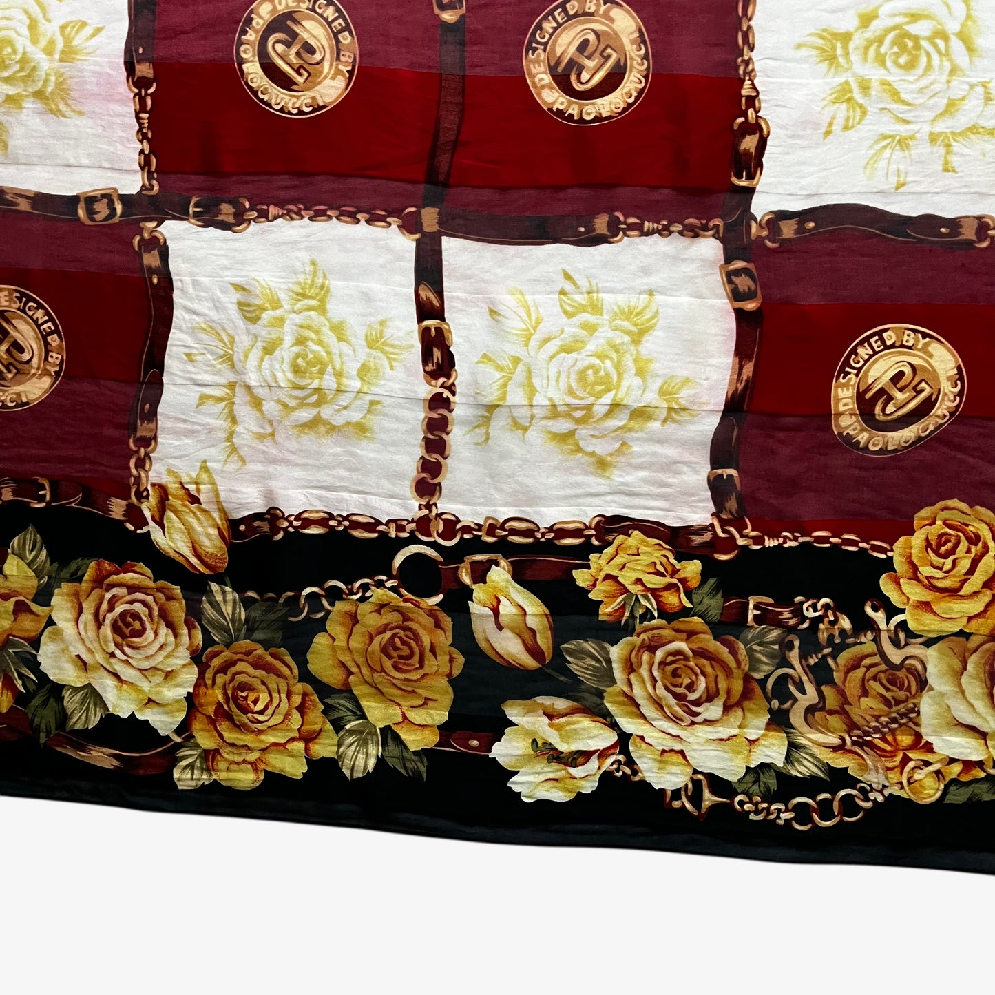 Floral trim on a women's vintage 80s Paolo Gucci black silk scarf featuring a checkered and equestrian buckle print.