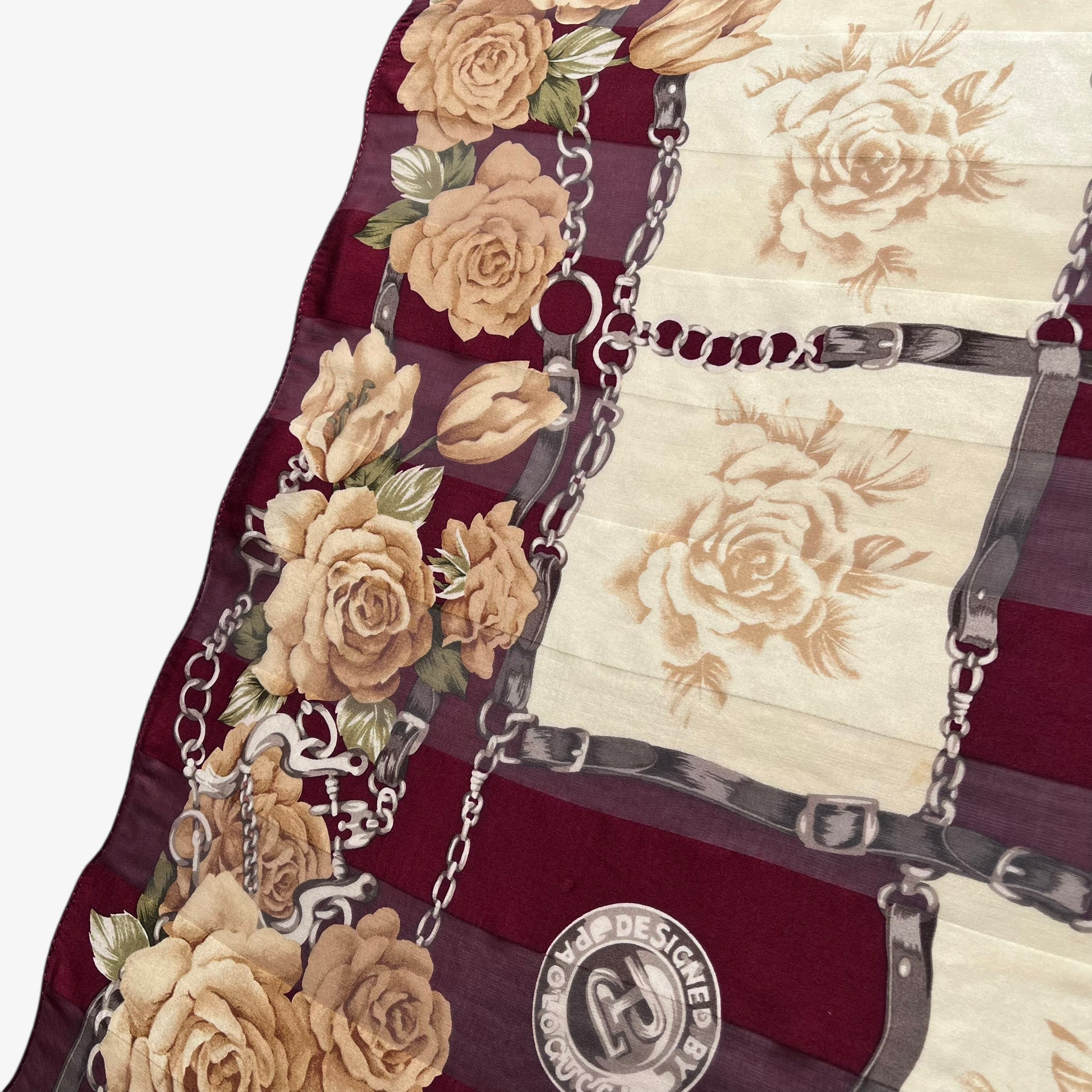 Patina on women's vintage 90s Paolo Gucci equestrian buckle and floral checkered print red silk scarf.