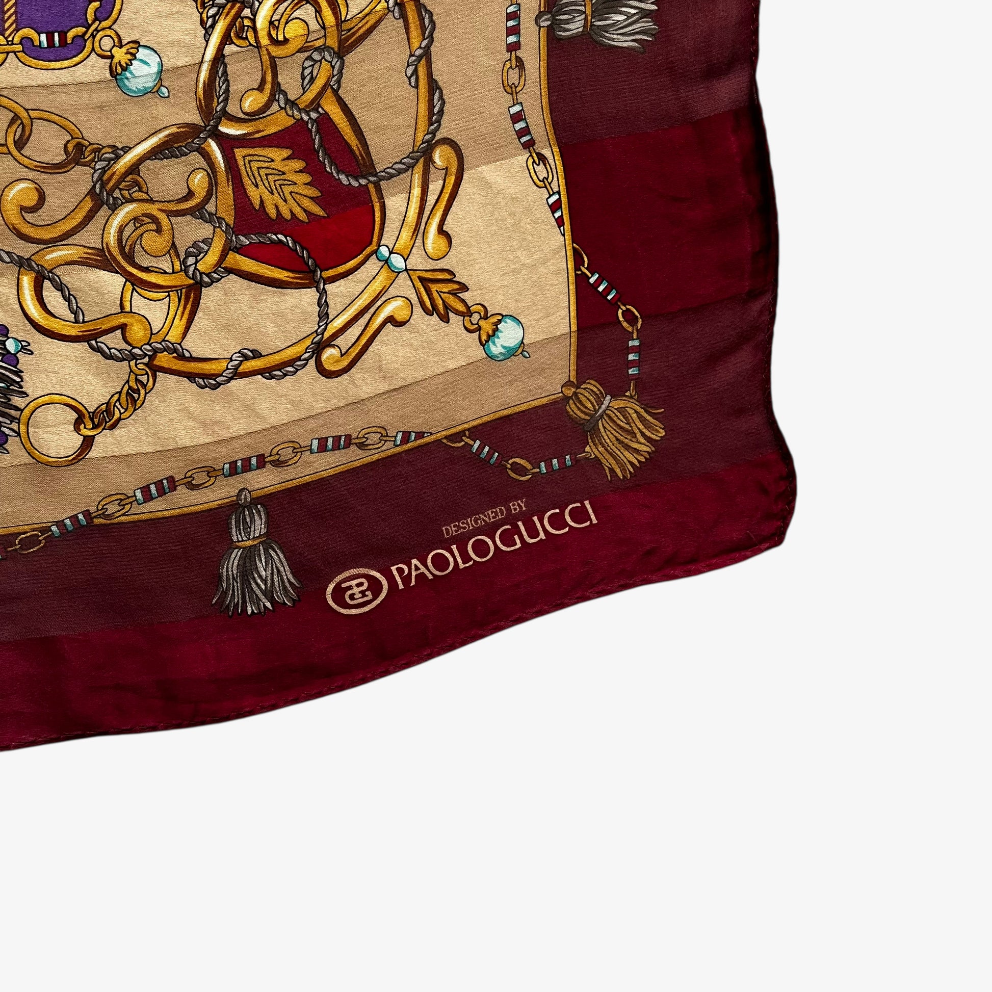 Paolo Gucci spell out printed logo on a women's vintage 80s red silk scarf features a gold medallion chain and purple tartan pattern.