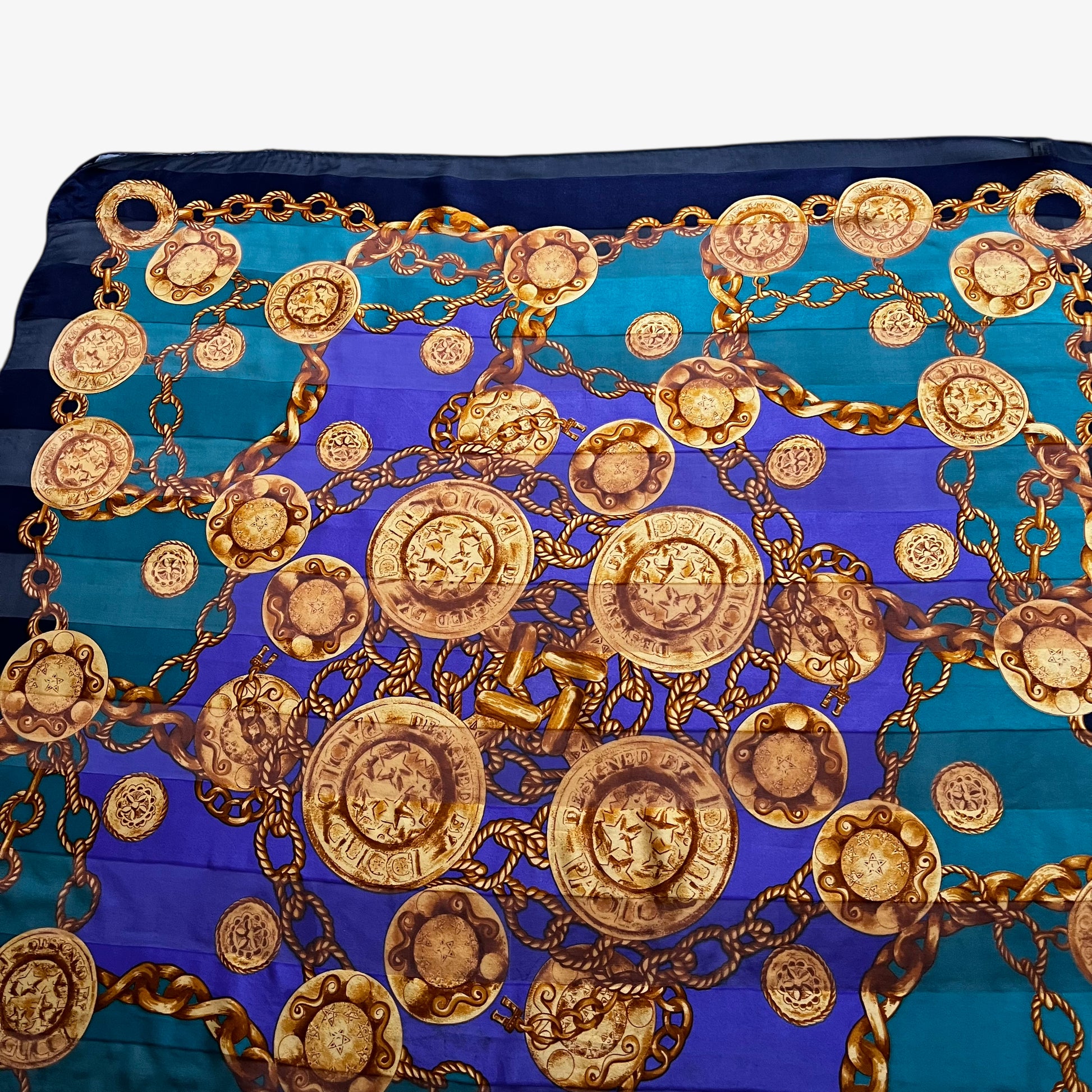Close up of gold medallion chain print of women's vintage 90s Paolo Gucci green and purple silk scarf.