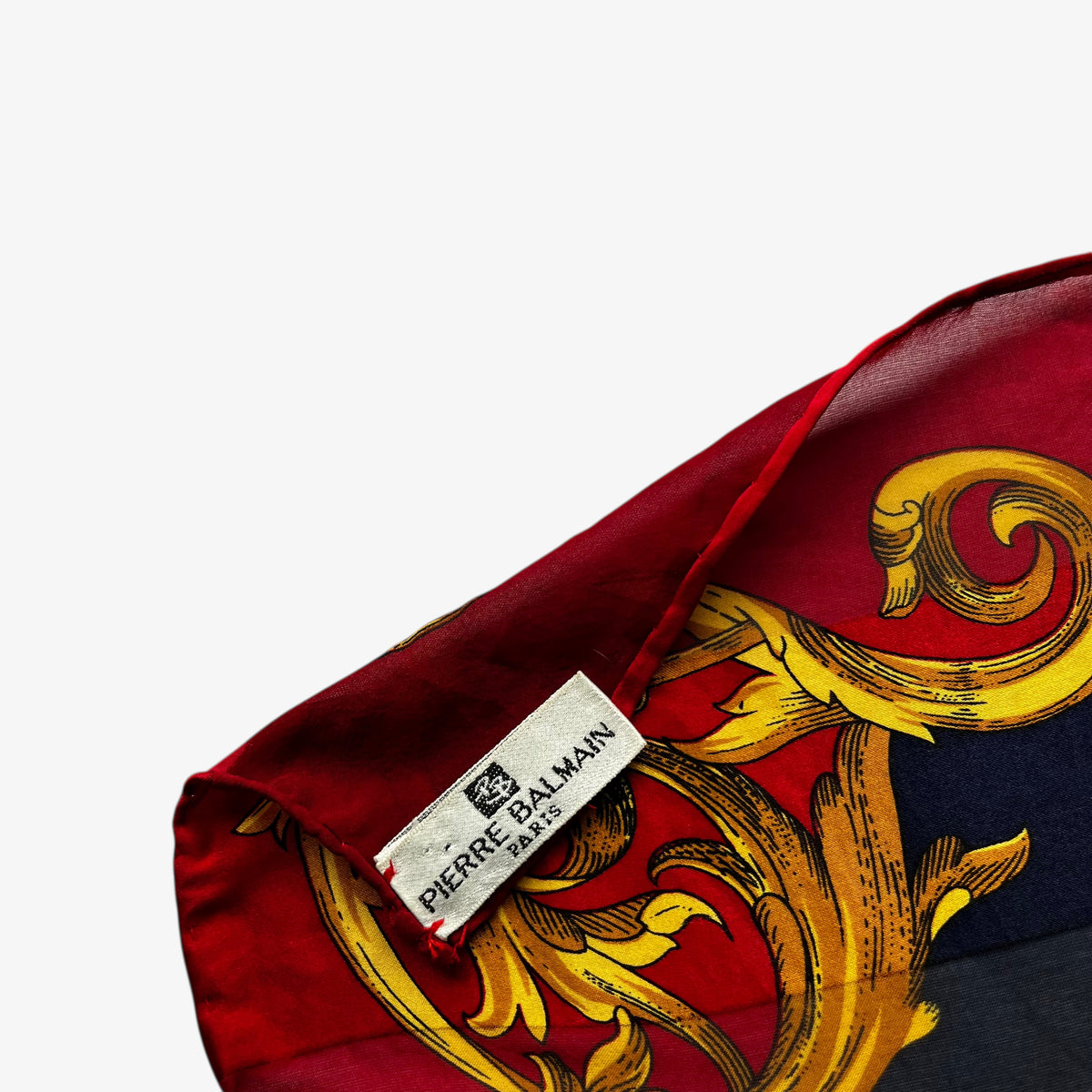 Pierre Balmain Paris label on a women's vintage 80s silk scarf featuring a gold royal medallion and polka dot print.