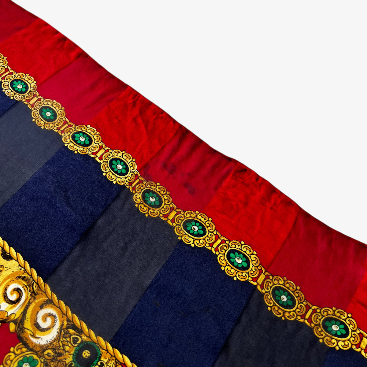 Wear to the side of a women's vintage 80s Pierre Balmain silk scarf featuring a gold royal medallion and polka dot print.