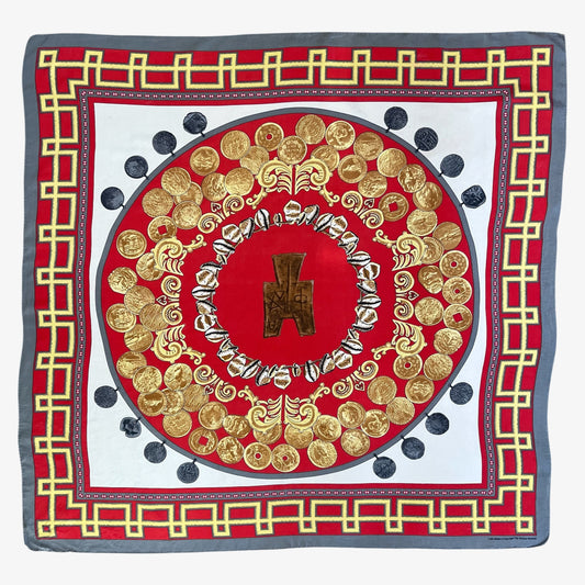 A square silk scarf featuring an intricate circular medallion design in red, gold, and white, framed by a grey border with a gold coin pattern.