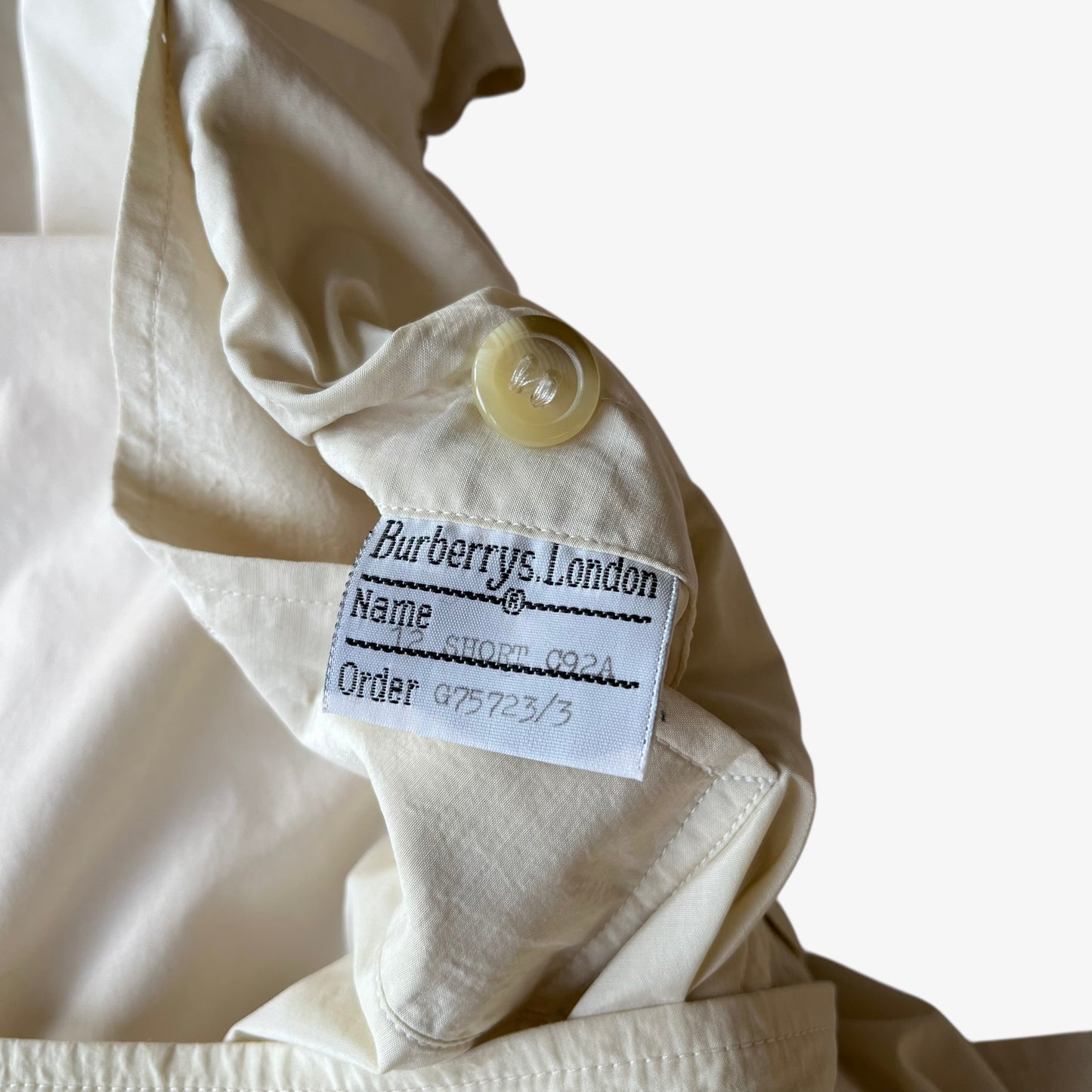 Burberrys London label stitched inside of women's vintage 80s double breasted cream trench coat.