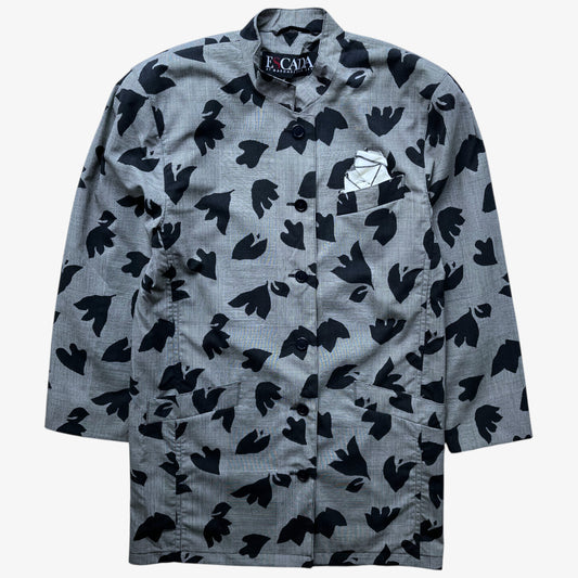 A grey long-sleeve vintage 80s Escada wool coat with a black abstract floral pattern, featuring a pointed collar, front button closure, and a geometric white pocket square in the chest pocket.