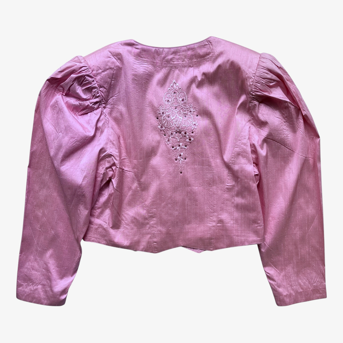A pink trachten jacket with puffed sleeves and a decorative beaded embellishment on the back, shown against a plain light background.