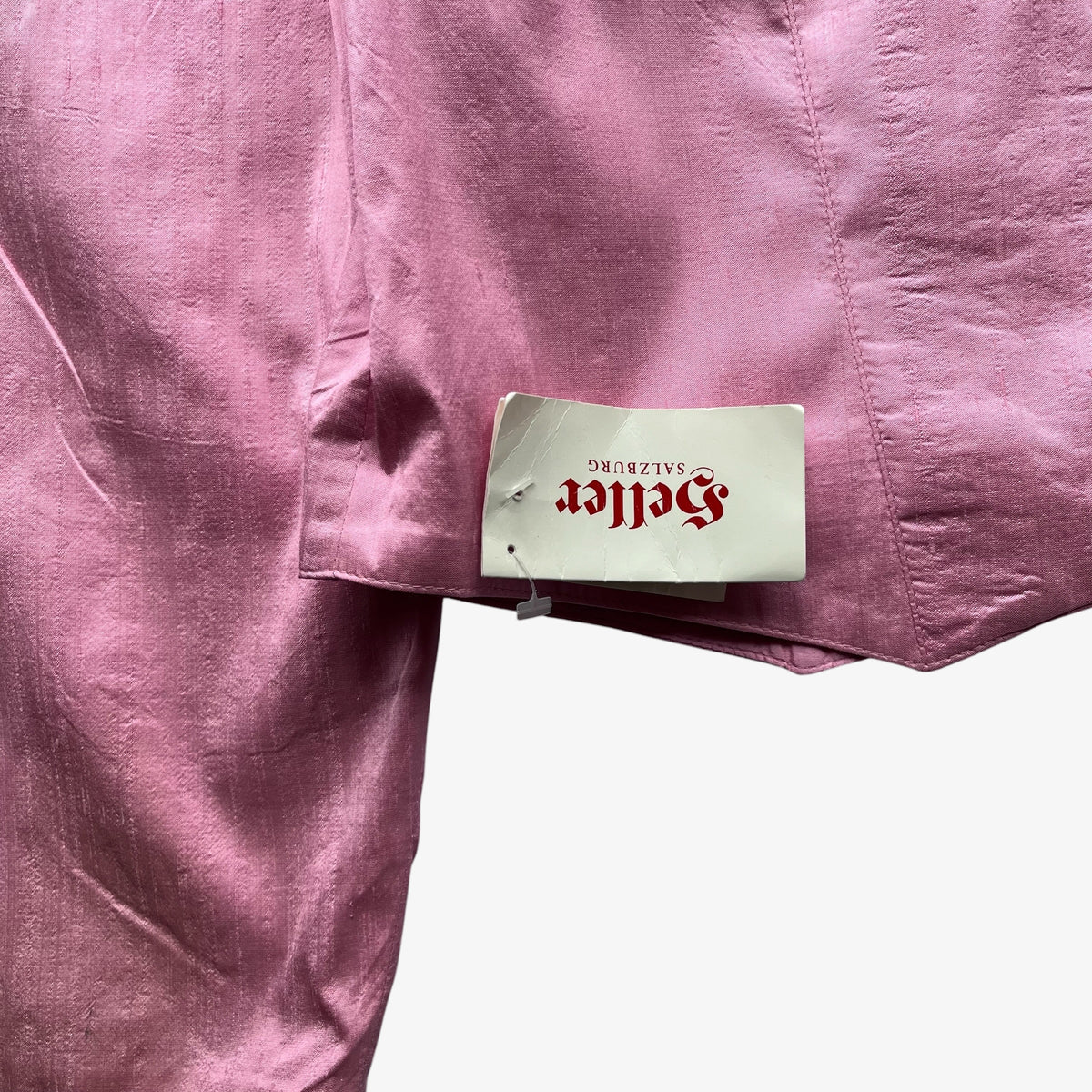 A close-up of dusty pink fabric with a white brand tag reading 'Heller Salzburg' in red gothic lettering.
