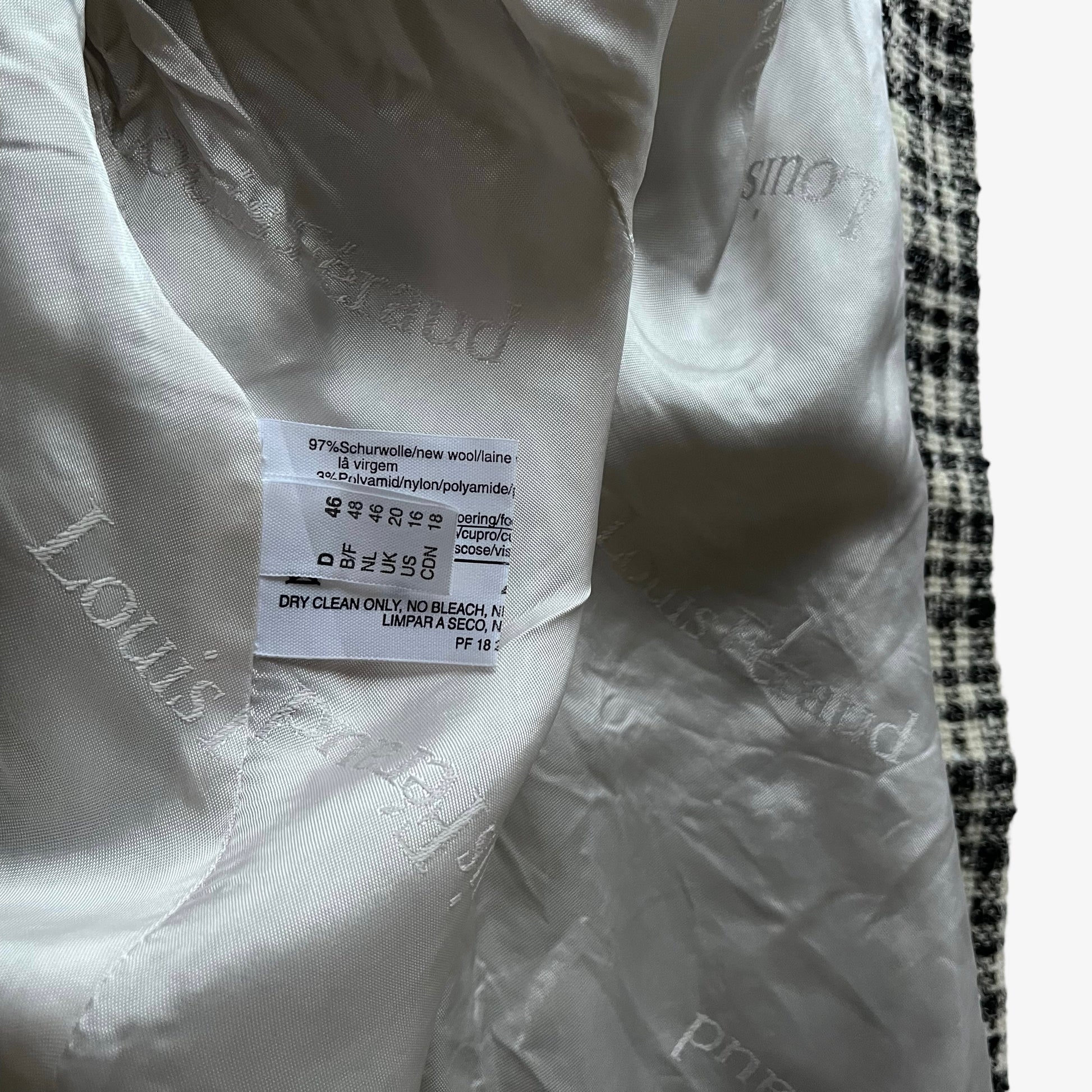 Close up of size label stitched inside of a vintage 80s women's Louis Feraud cream and black striped tartan blazer.