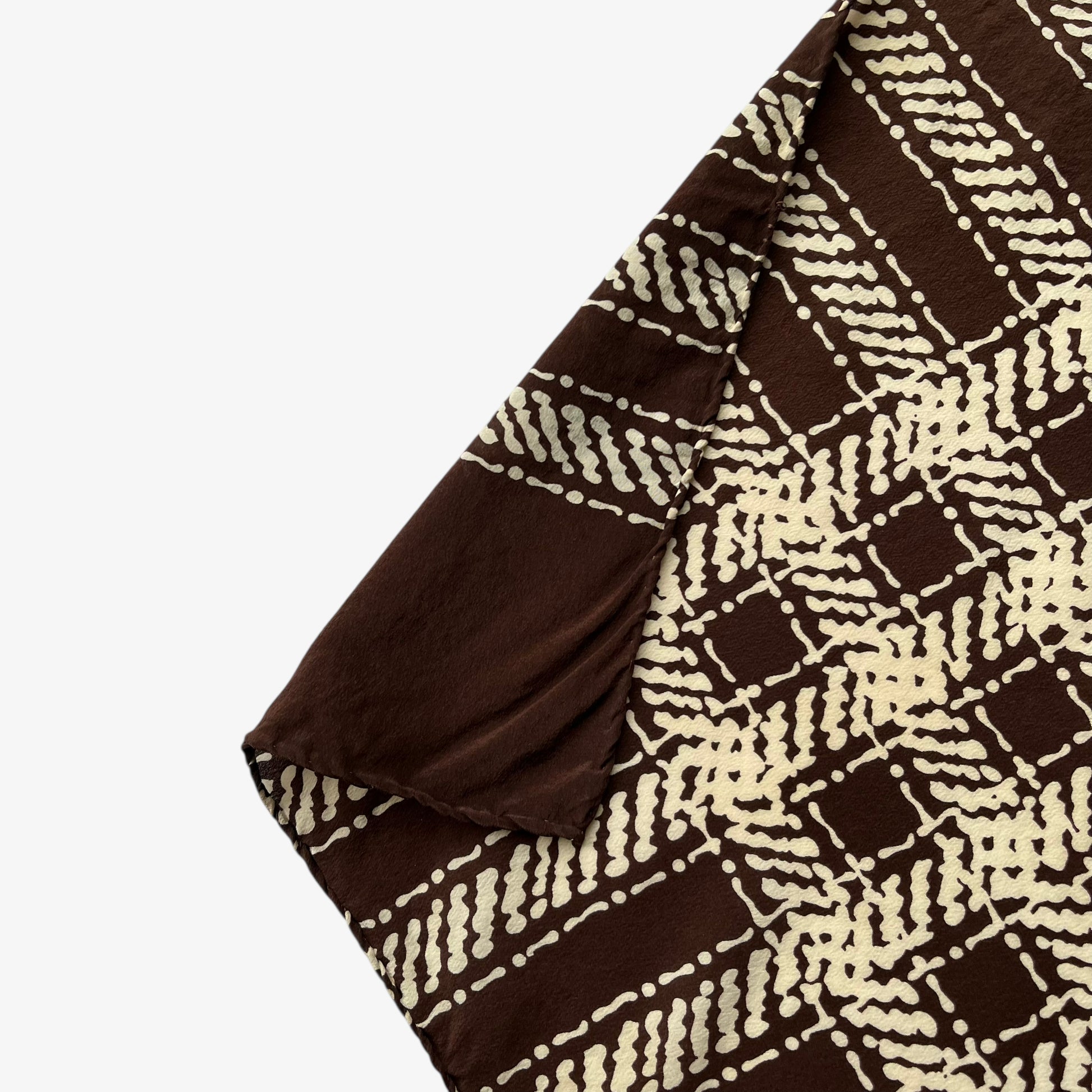Hand rolled edges on a women's vintage 80s Yves Saint Laurent brown checkered print silk scarf with a YSL motif.