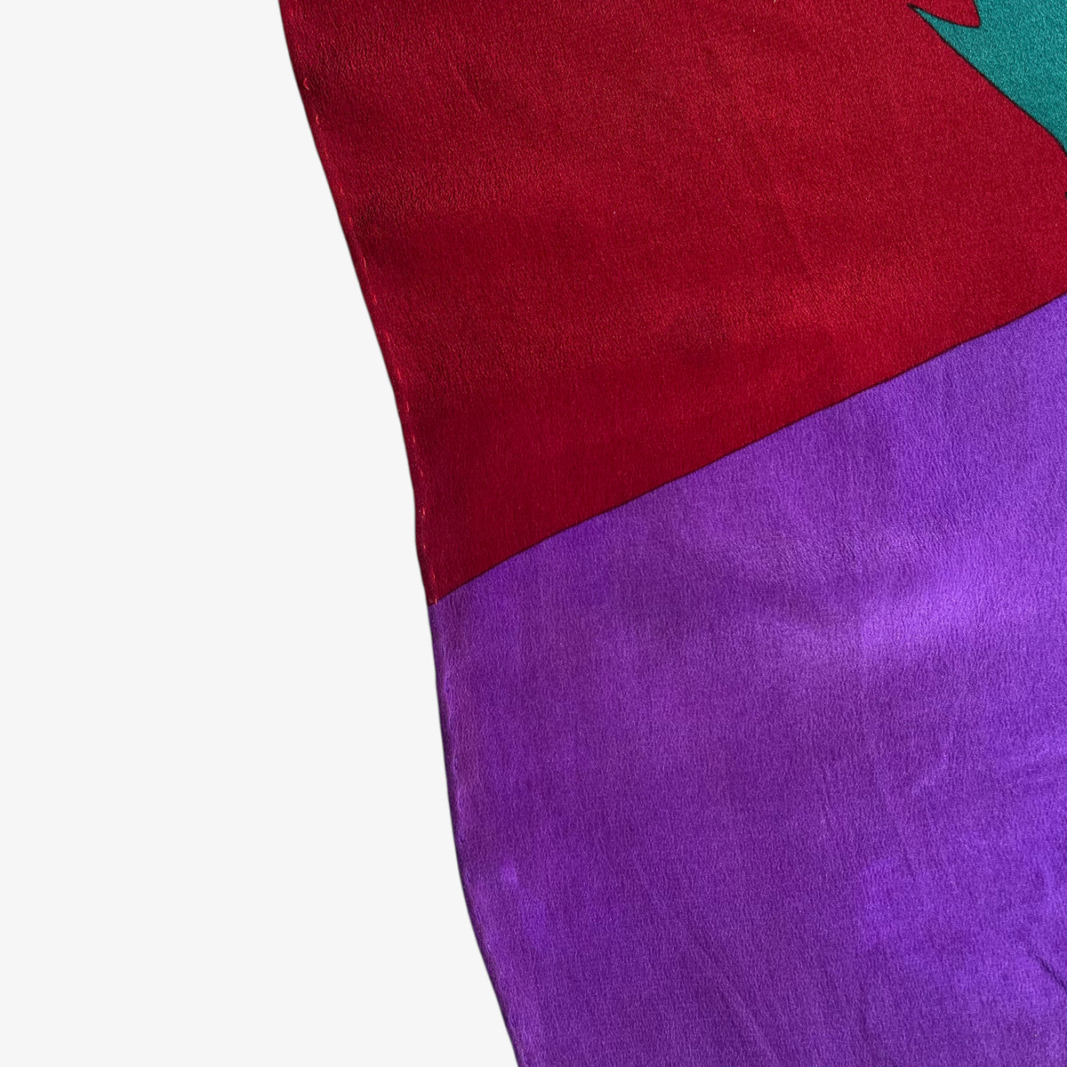 Hem of women's vintage 80s Yves Saint Laurent colourful abstract print green silk scarf.