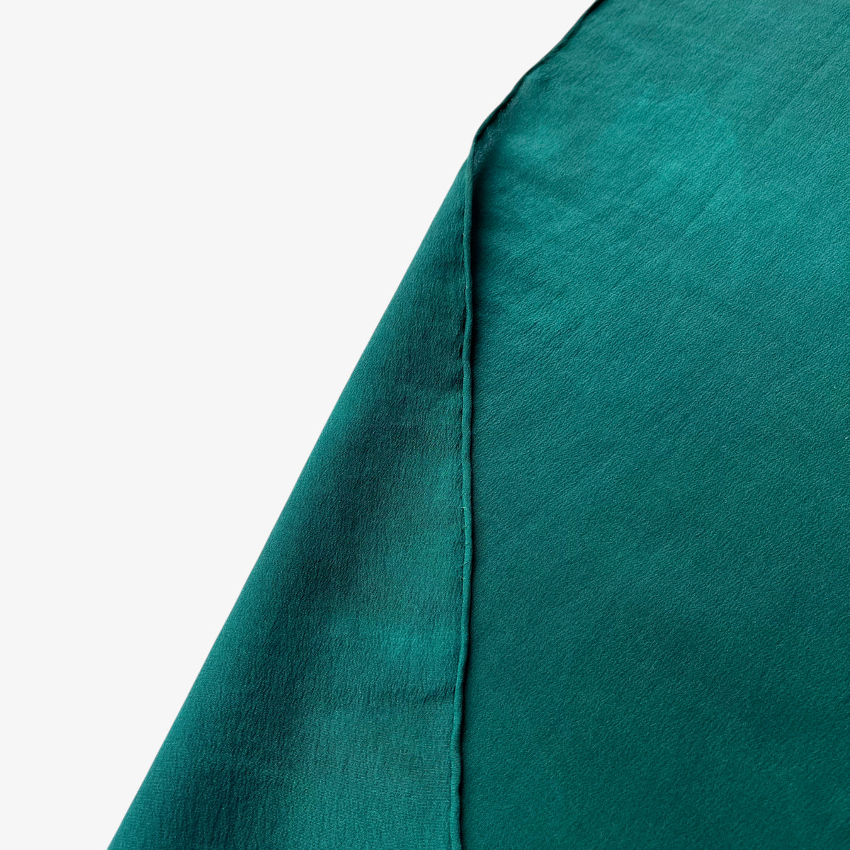 Hand rolled edges of women's vintage 80s Yves Saint Laurent colourful abstract print green silk scarf.