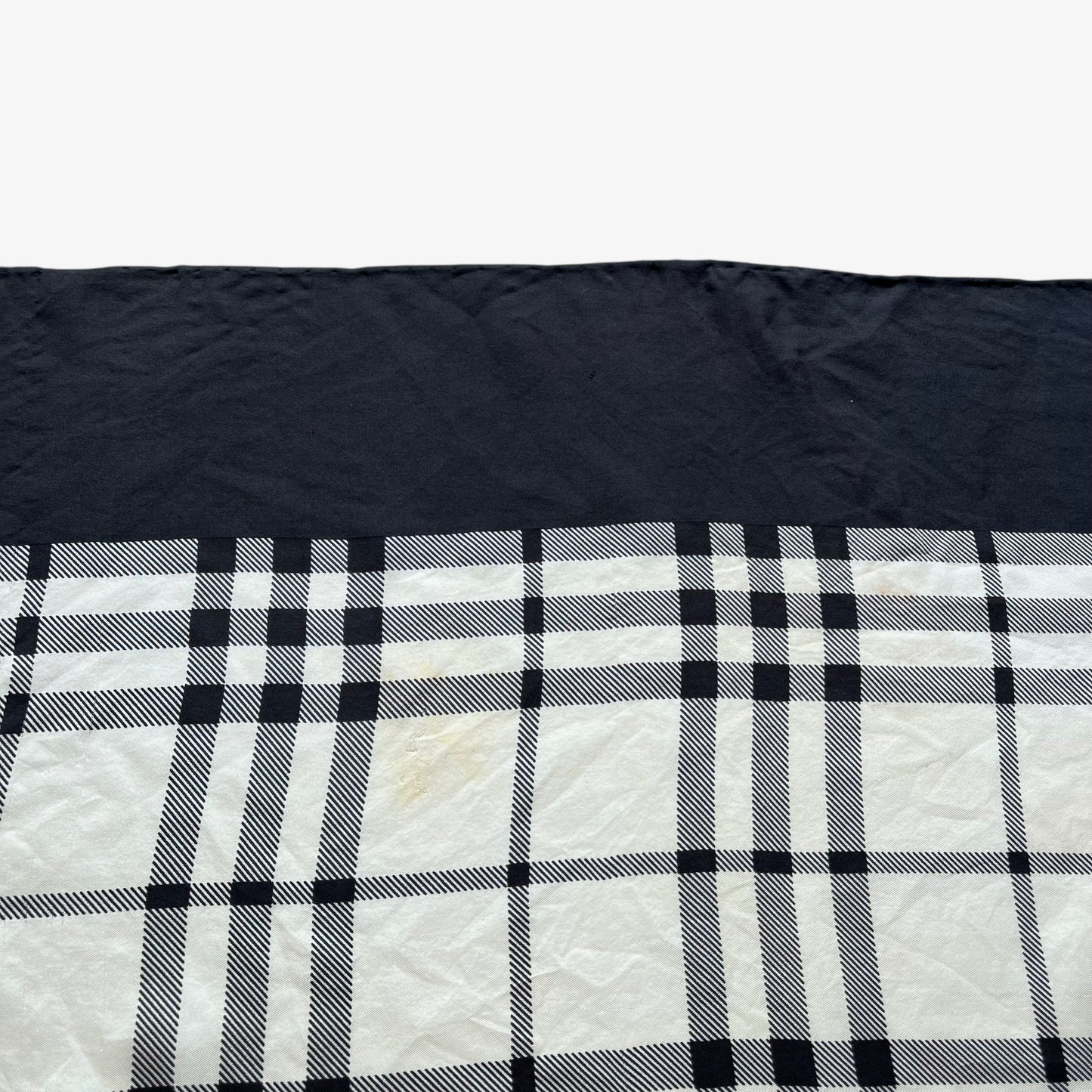 Hem of women's vintage 90s Burberry black nova check print silk scarf.