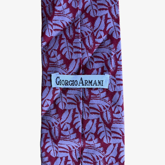 Label of vintage 90s Giorgio Armani red silk tie with a tropical leaf print pattern.