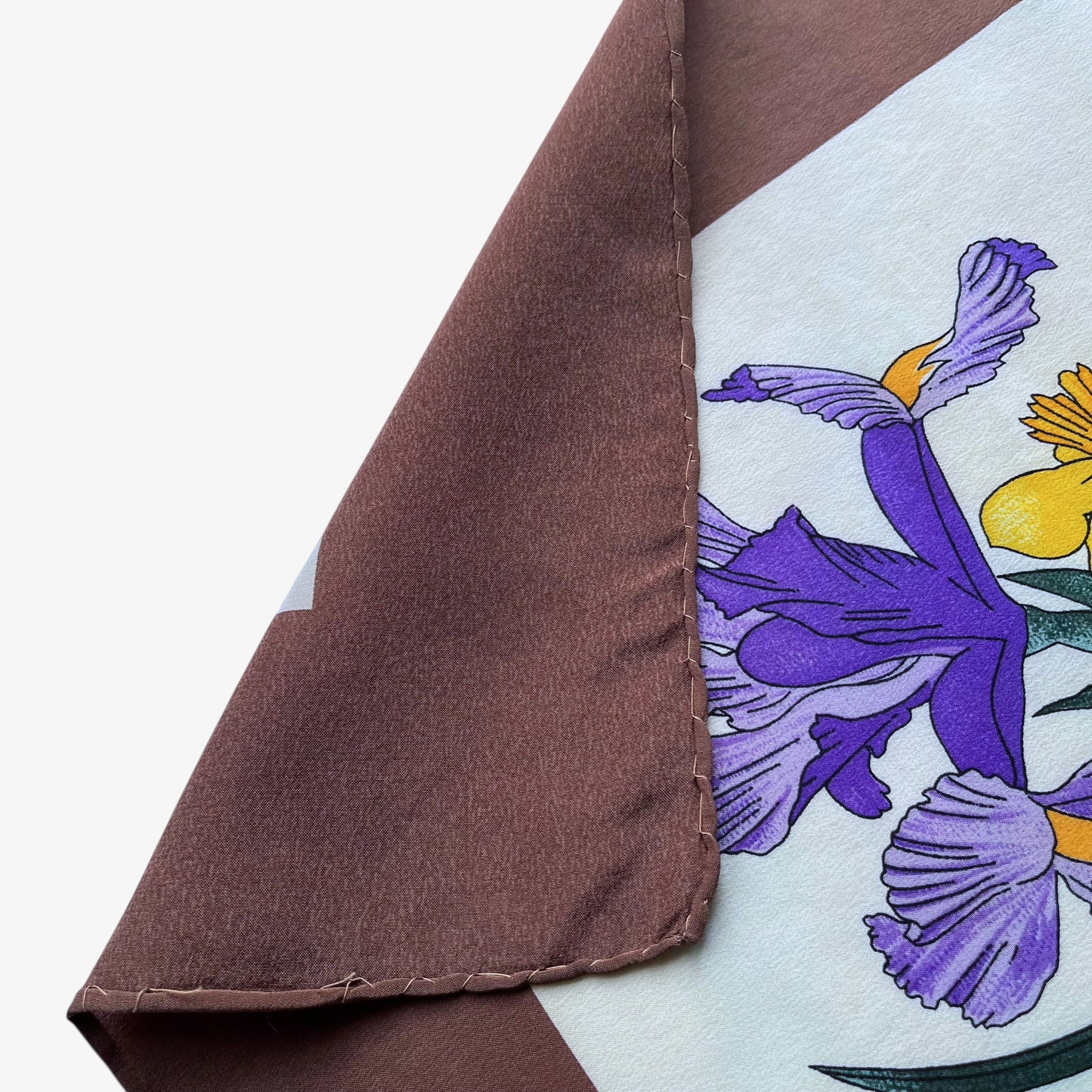 Hand rolled edges of women's 90s vintage Gucci colourful floral and insect print brown silk scarf designed by Vittorio Accornero.