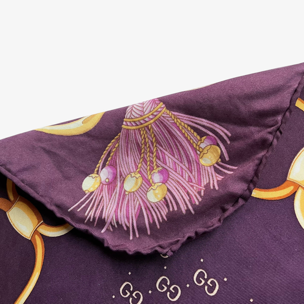 Hand rolled edges on women's vintage 90s Gucci gold tassel chain print purple silk scarf with a geometric interlocking GG pattern.