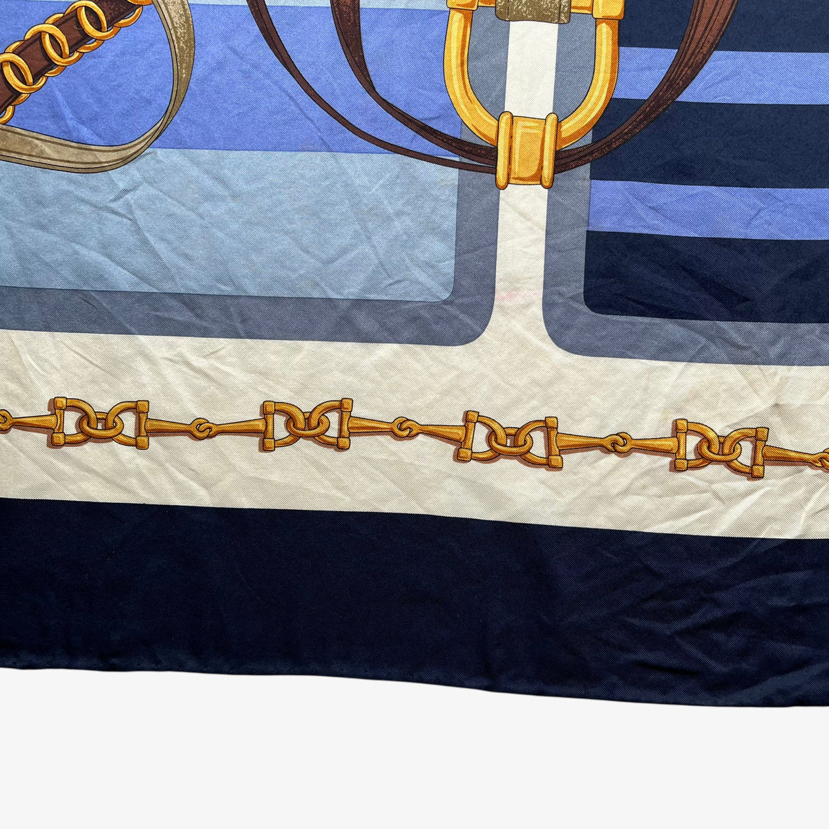 Hem on women's vintage 90s Lancel Paris gold equestrian horsebit print blue silk scarf featuring a striped design.