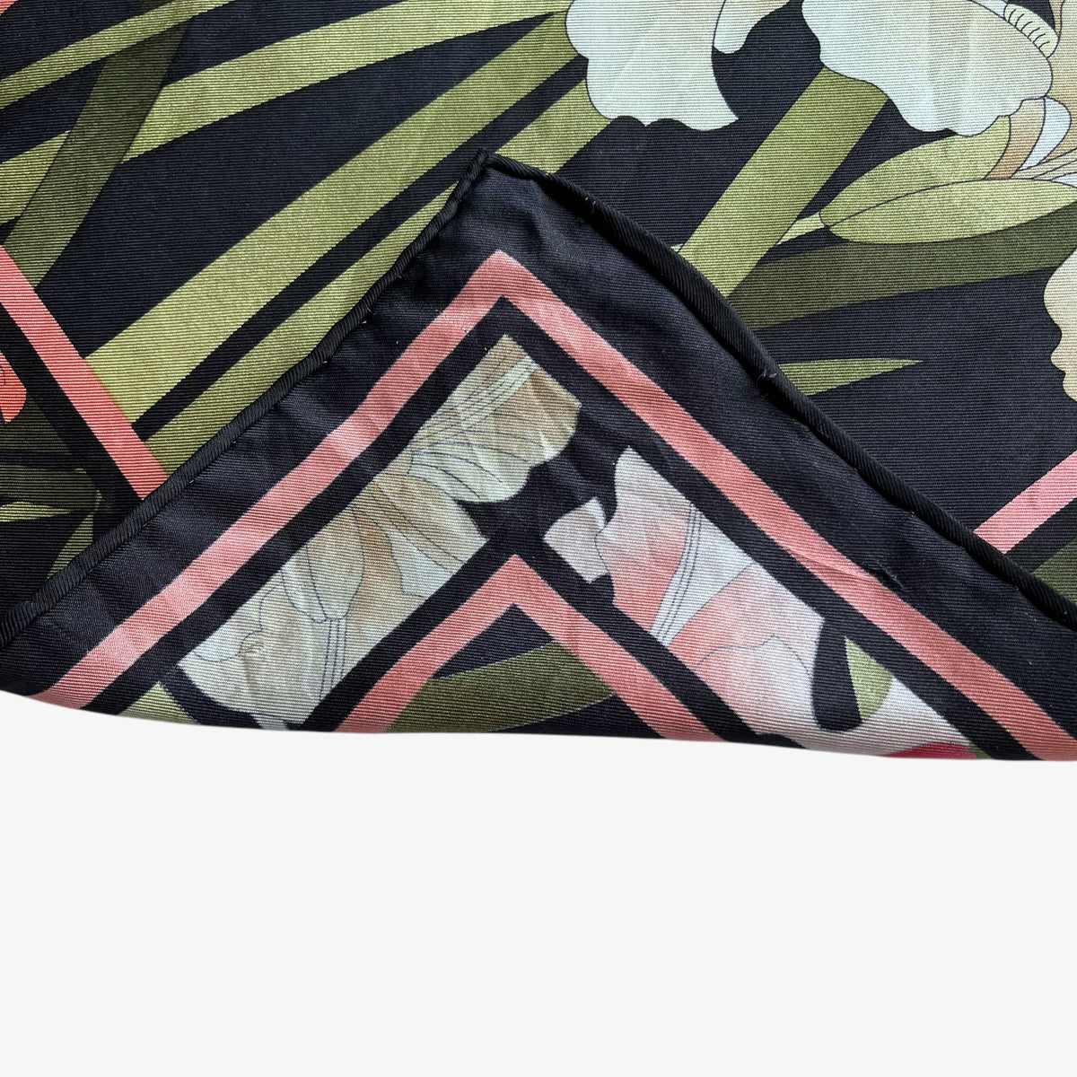 Hand rolled edges of vintage 90s women's Leonard Paris floral water colour painting print black silk scarf.